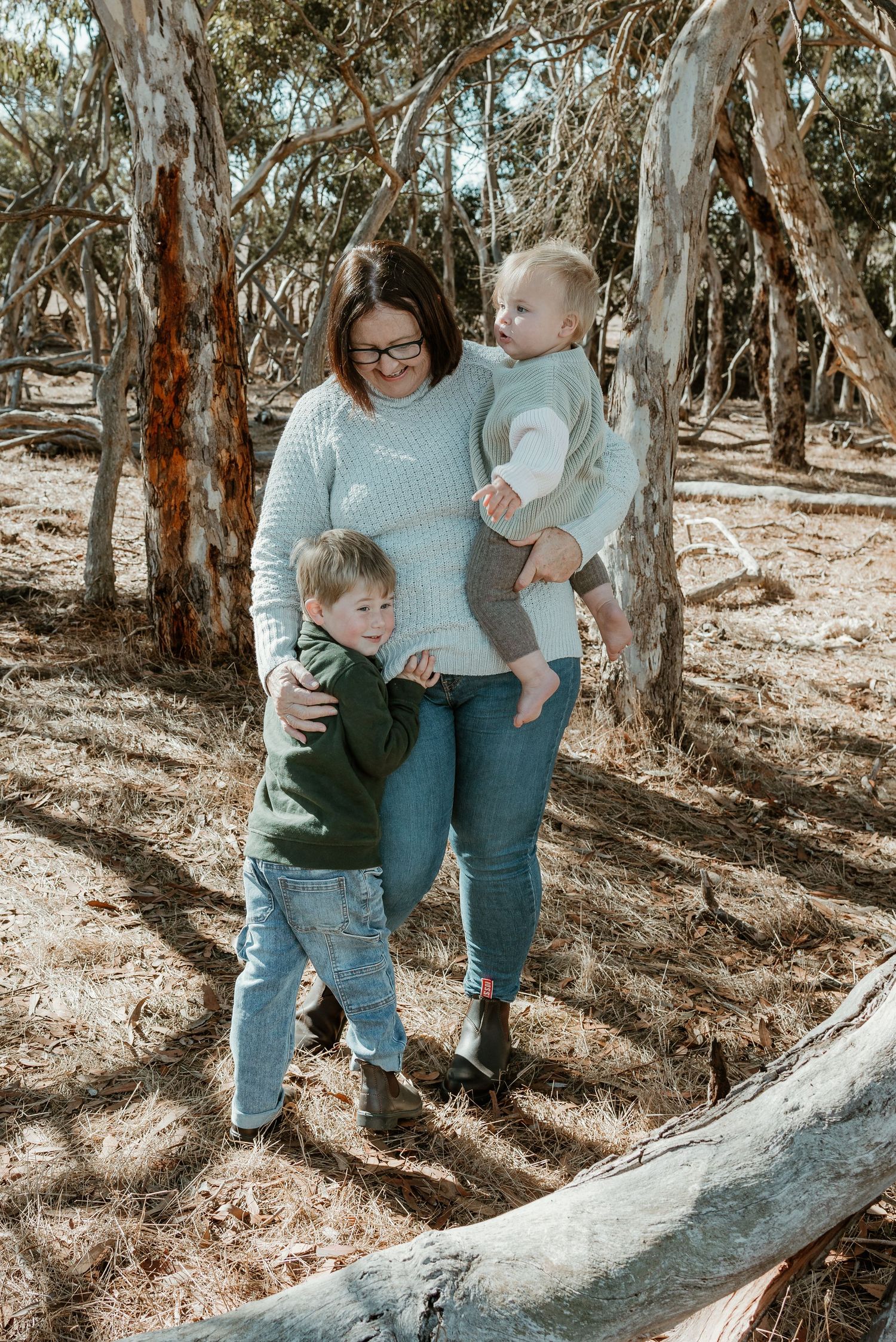 A tender family moment among eucalyptus trees in an Australian bush setting.