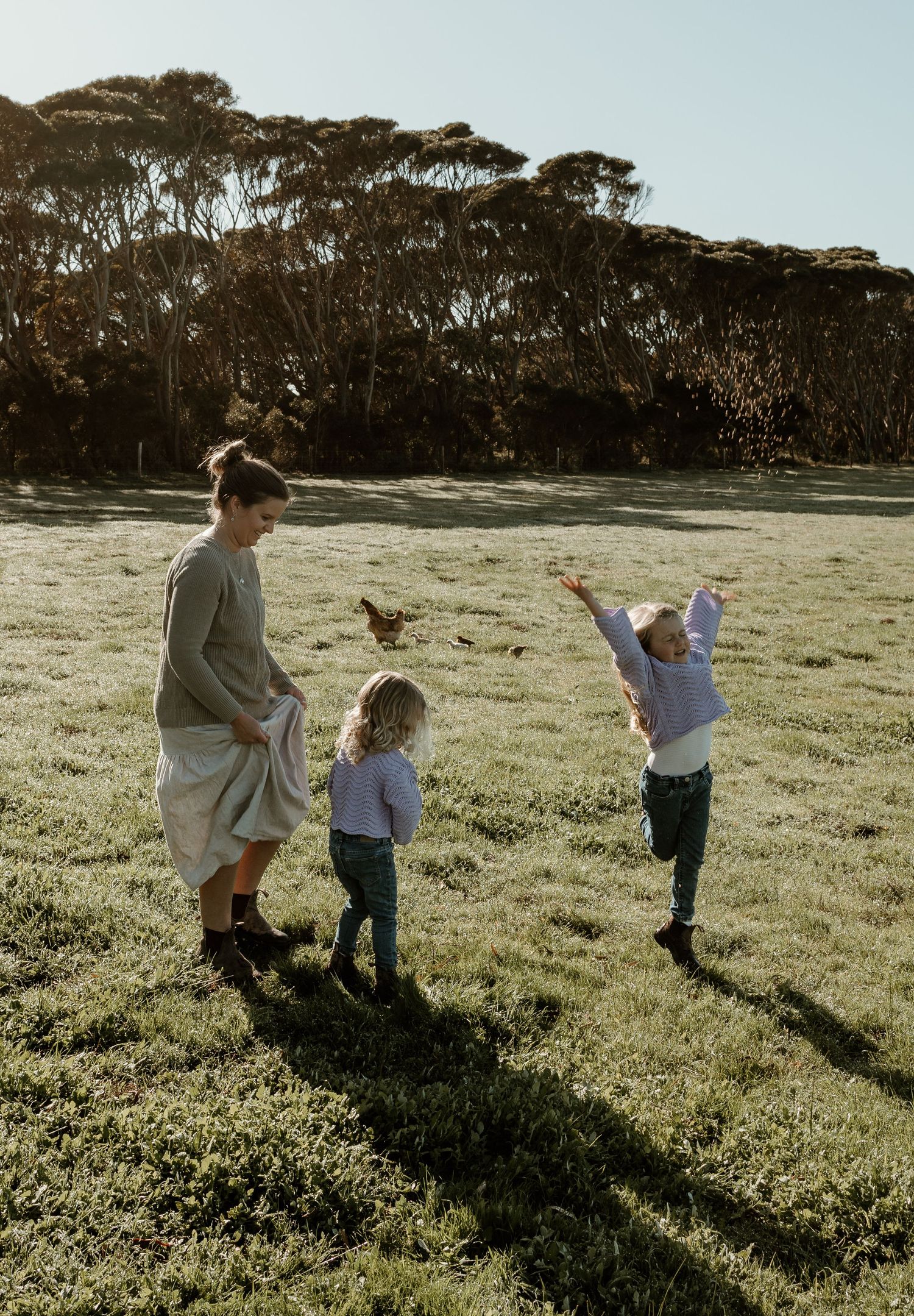 Family playing together in a sunny field with trees in the background. Kangaroo Island.