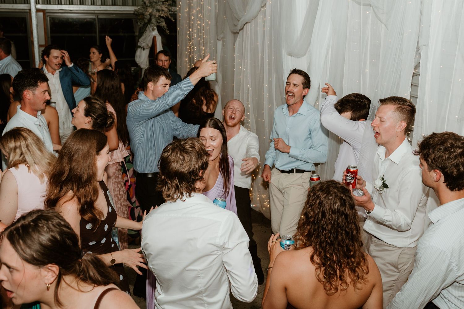 Guests dancing and celebrating joyfully at a lively indoor wedding reception party.
