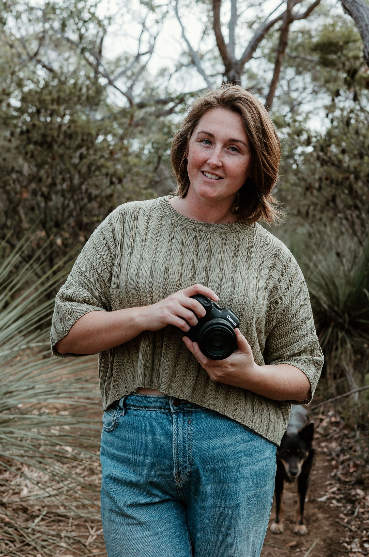 Rhyy holding her camera while posing in natural outdoor setting. Kangaroo Island.