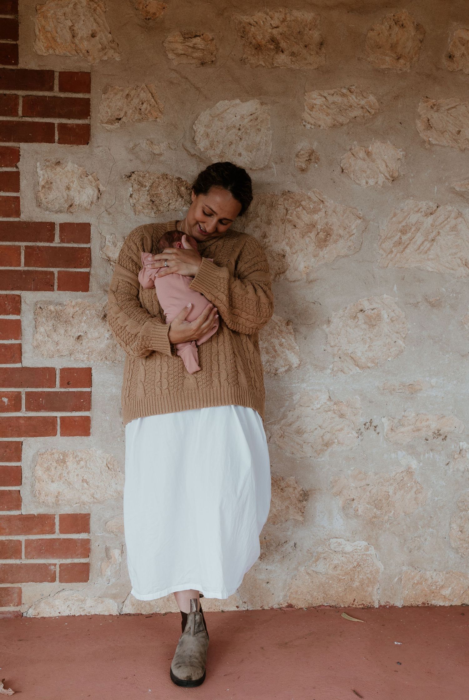 A gentle moment captured against a textured stone and brick wall.