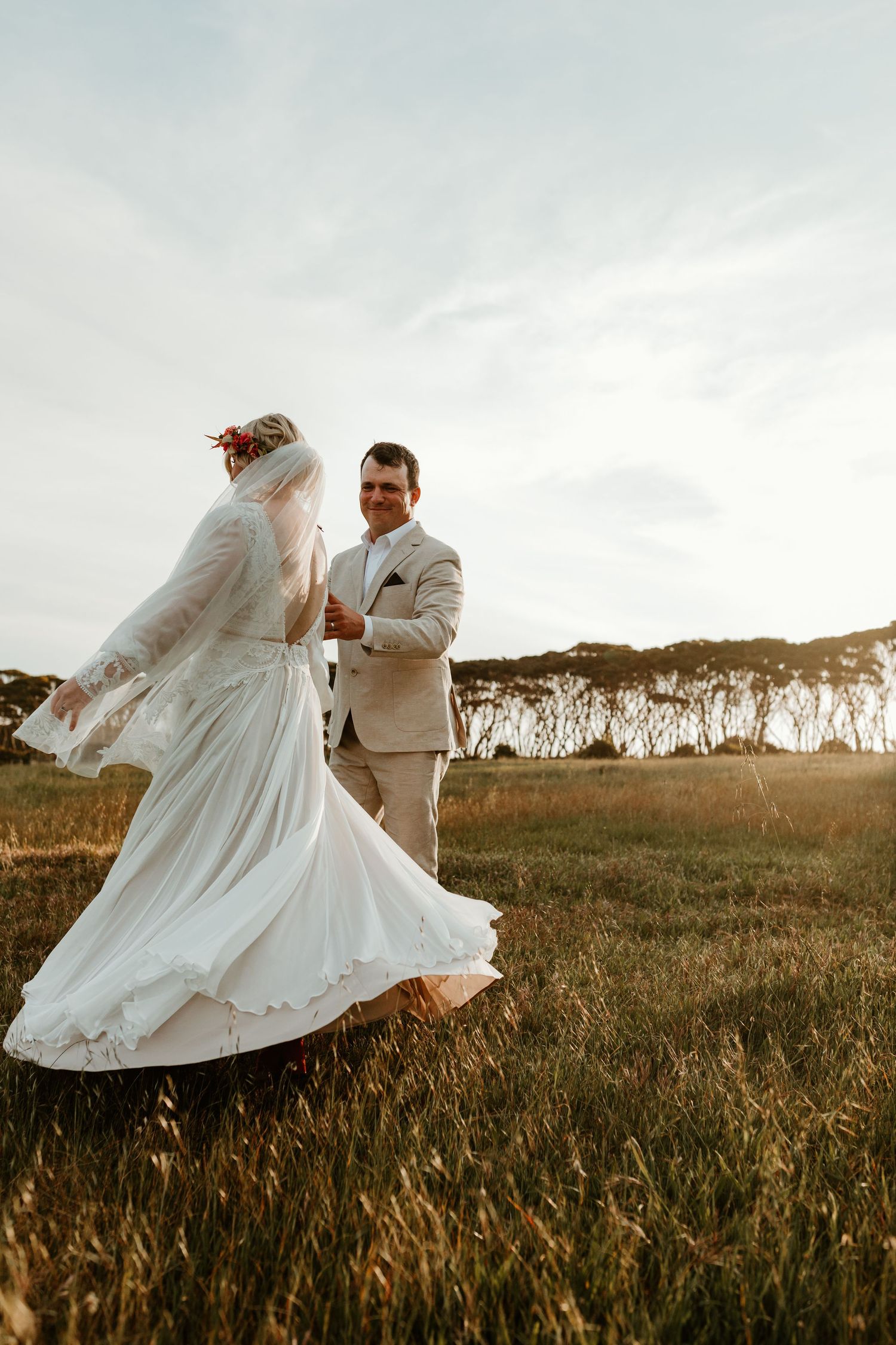 Couple dancing in a field at golden hour with flowing white wedding dress.