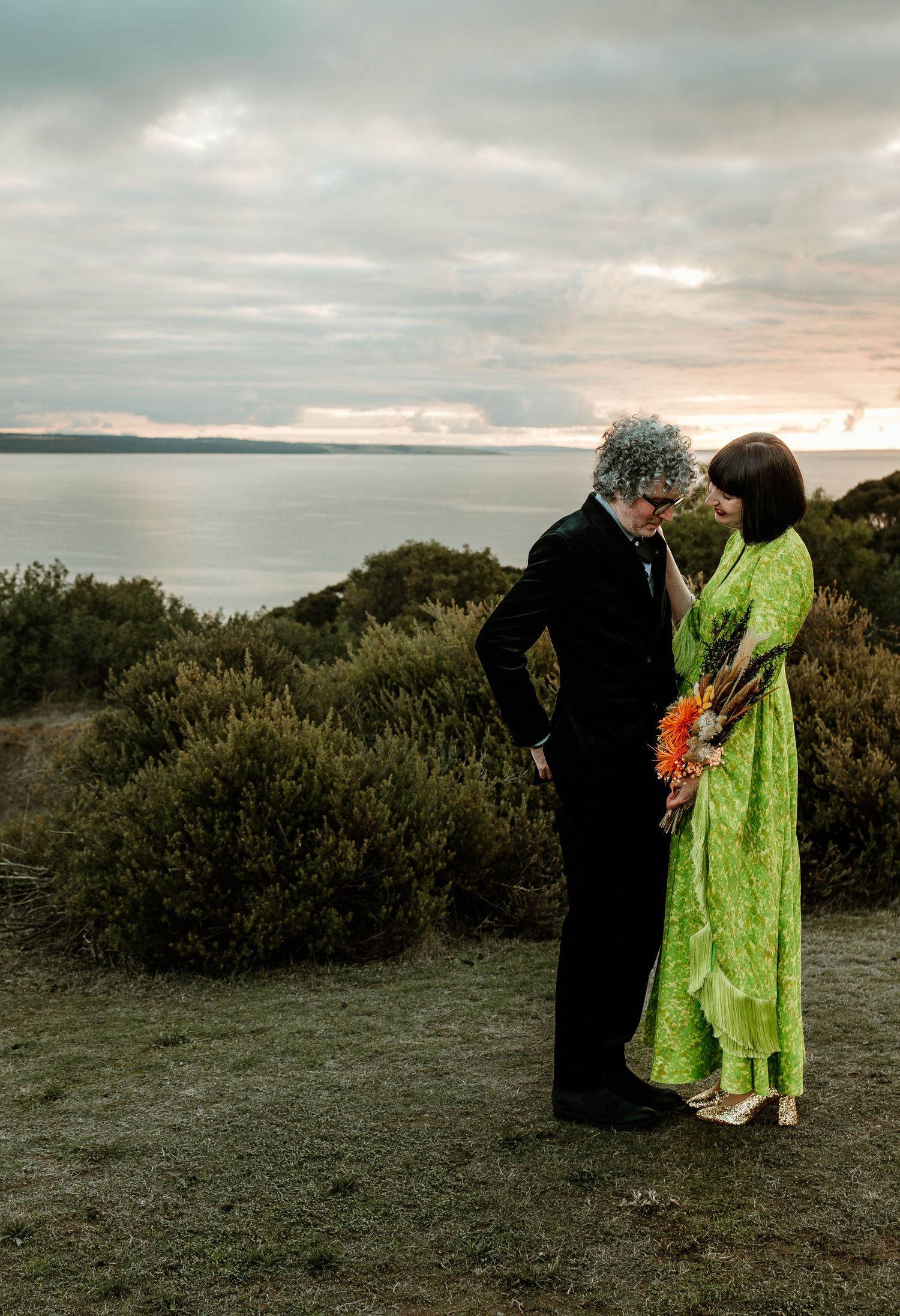 Couple shares an intimate moment at sunset overlooking a serene coastline.