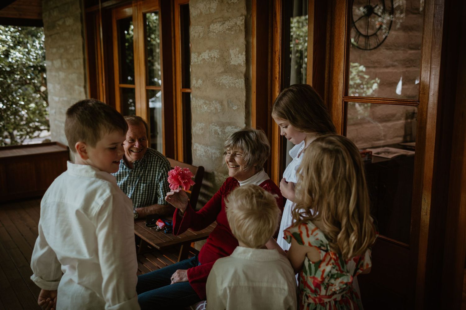 Family gathering in cozy rustic room with wooden windows and warm lighting.