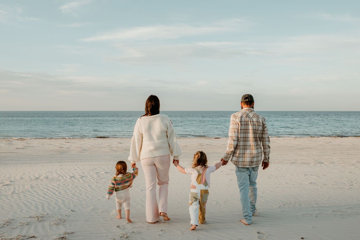 Family walking together hand in hand on Kangaroo Island sandy beach at sunset.