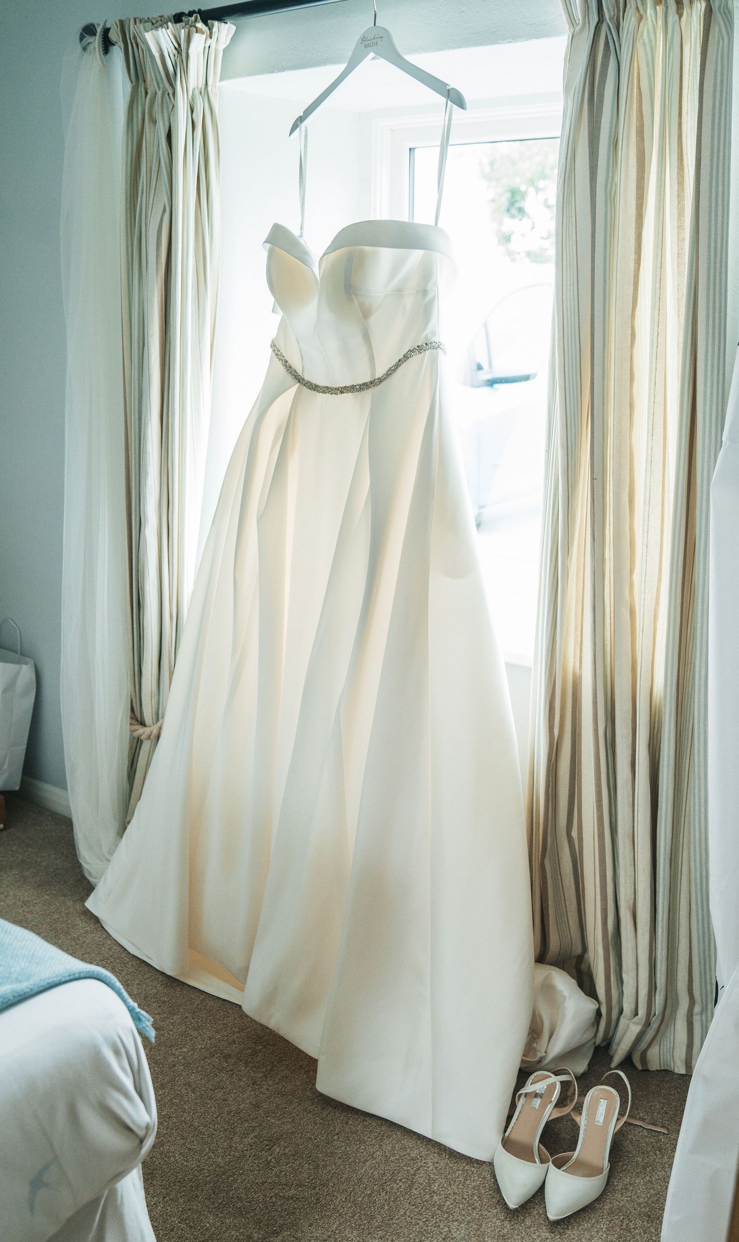 wedding dress hung up at Barff house country weddings, captured by a candid wedding photographer.