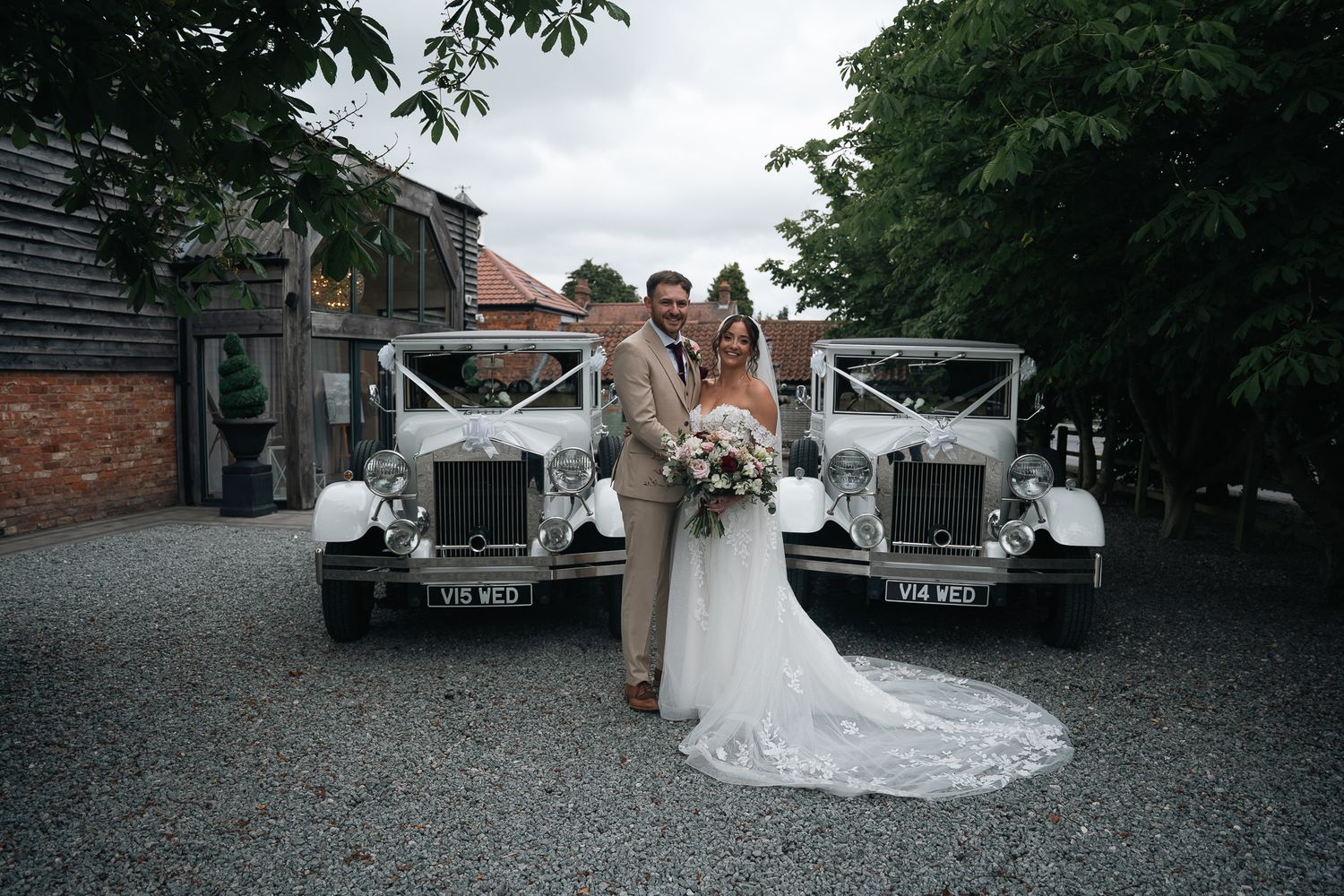 Bride and groom standing in front of vintage wedding cars at The Barn at Willerby Hill.