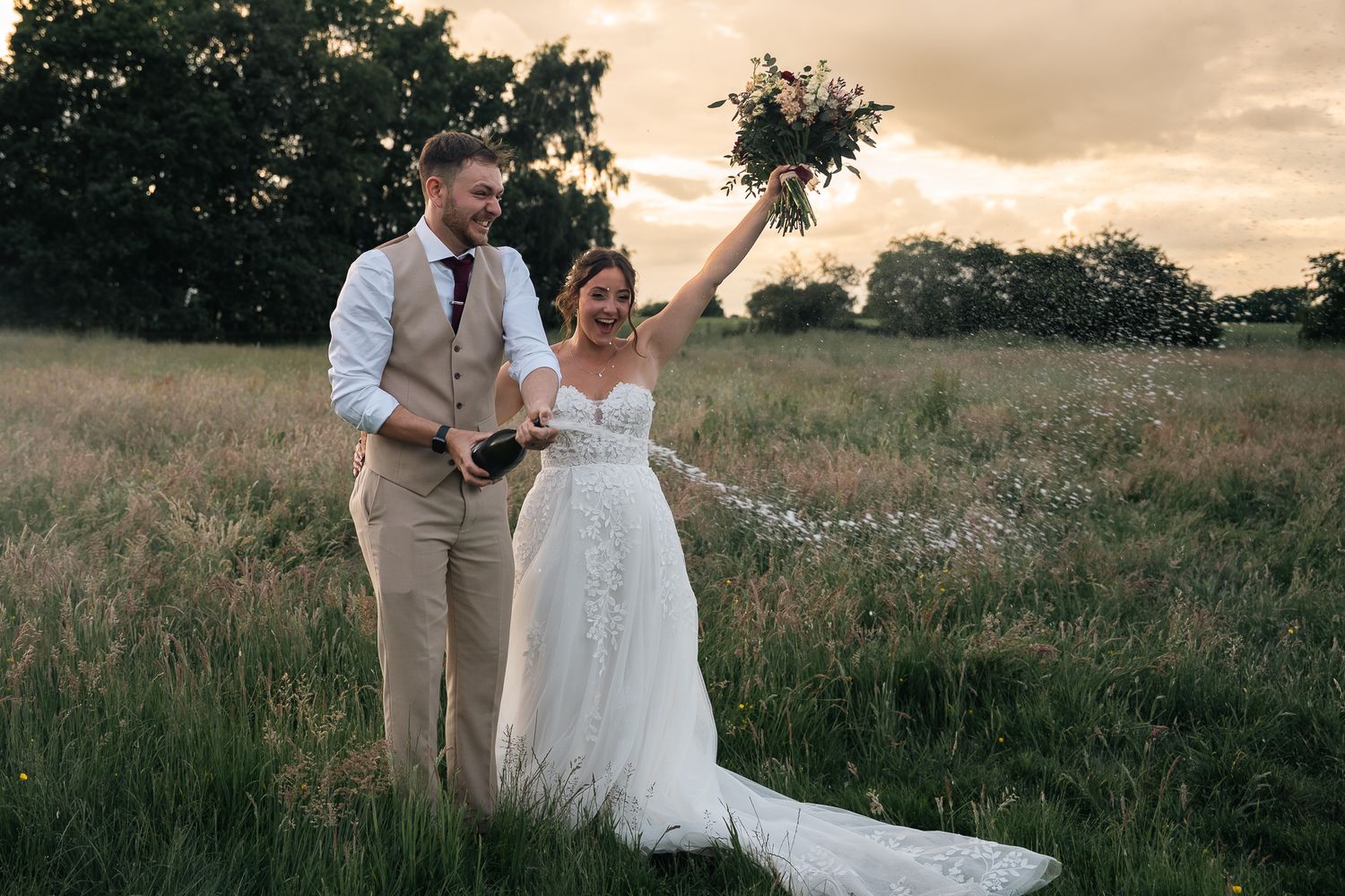 Bride and groom popping the champagne at sunset during the reception at The barn at Willerby Hill