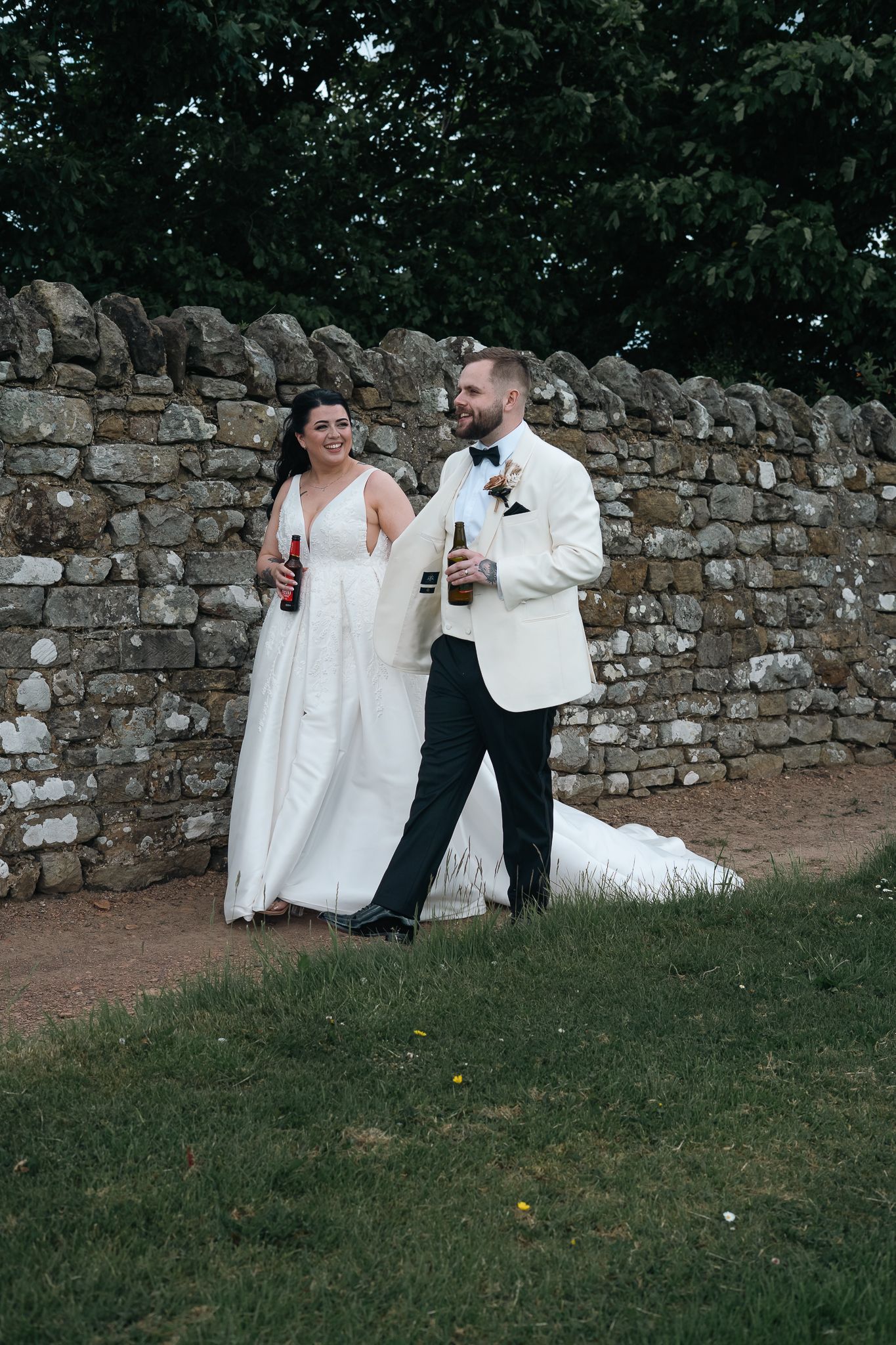 Bride and groom walking together beside the stone wall in the gardens at Grand Villa Heights.
