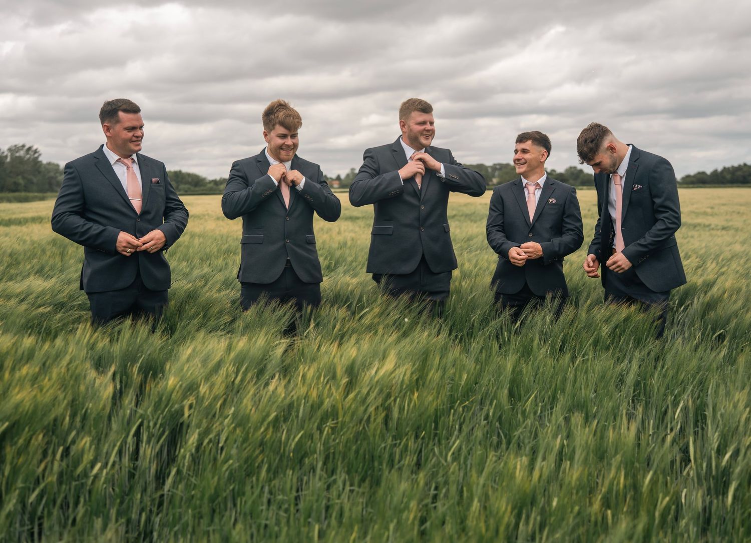 Groomsmen helping each other with their ties in his own field, captured by East Yorkshire wedding photographer