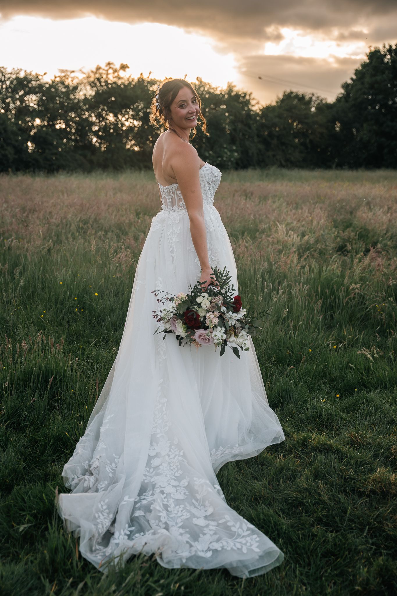 Bride stood holding her bouquet at sunset during the wedding reception at The Barn At Willerby Hill
