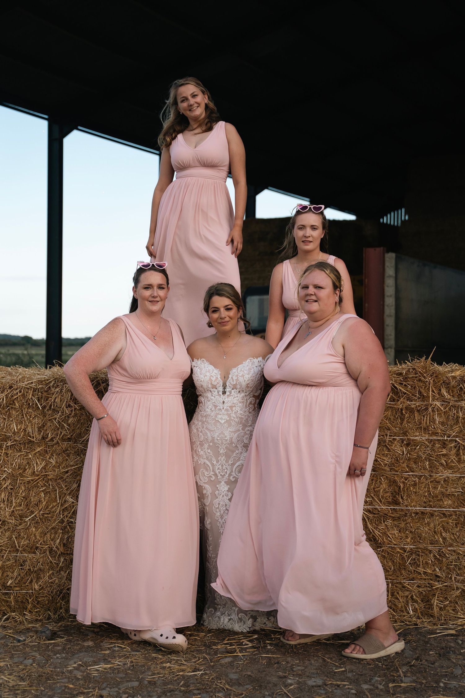 Bride and bridesmaids posing on haybales, taken by an East Yorkshire wedding Photographer