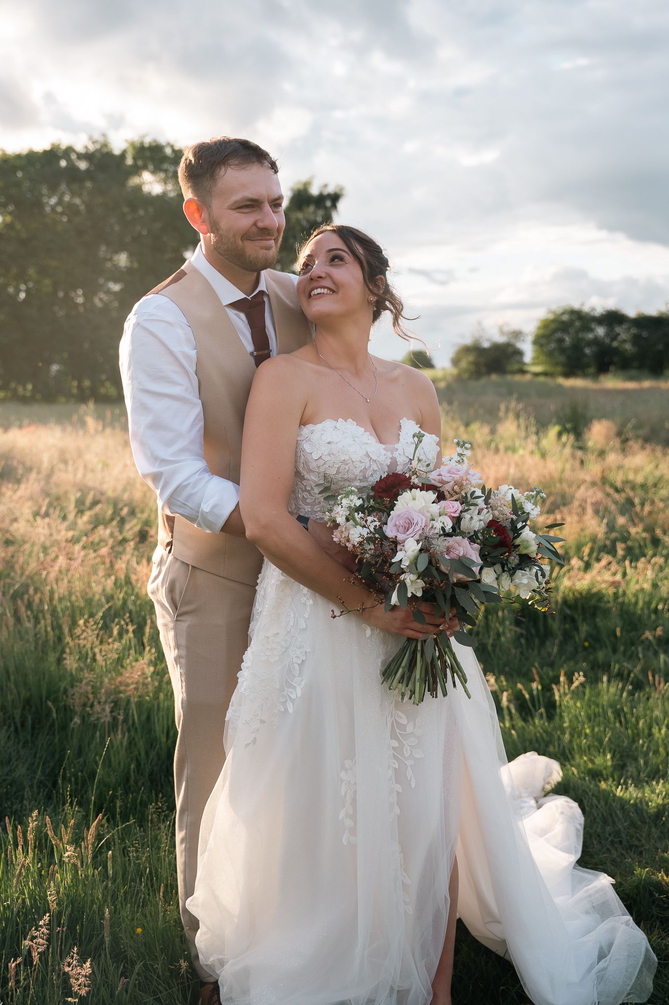 Bride and groom embracing in a wildflower meadow at The Barn at Willerby during sunset.