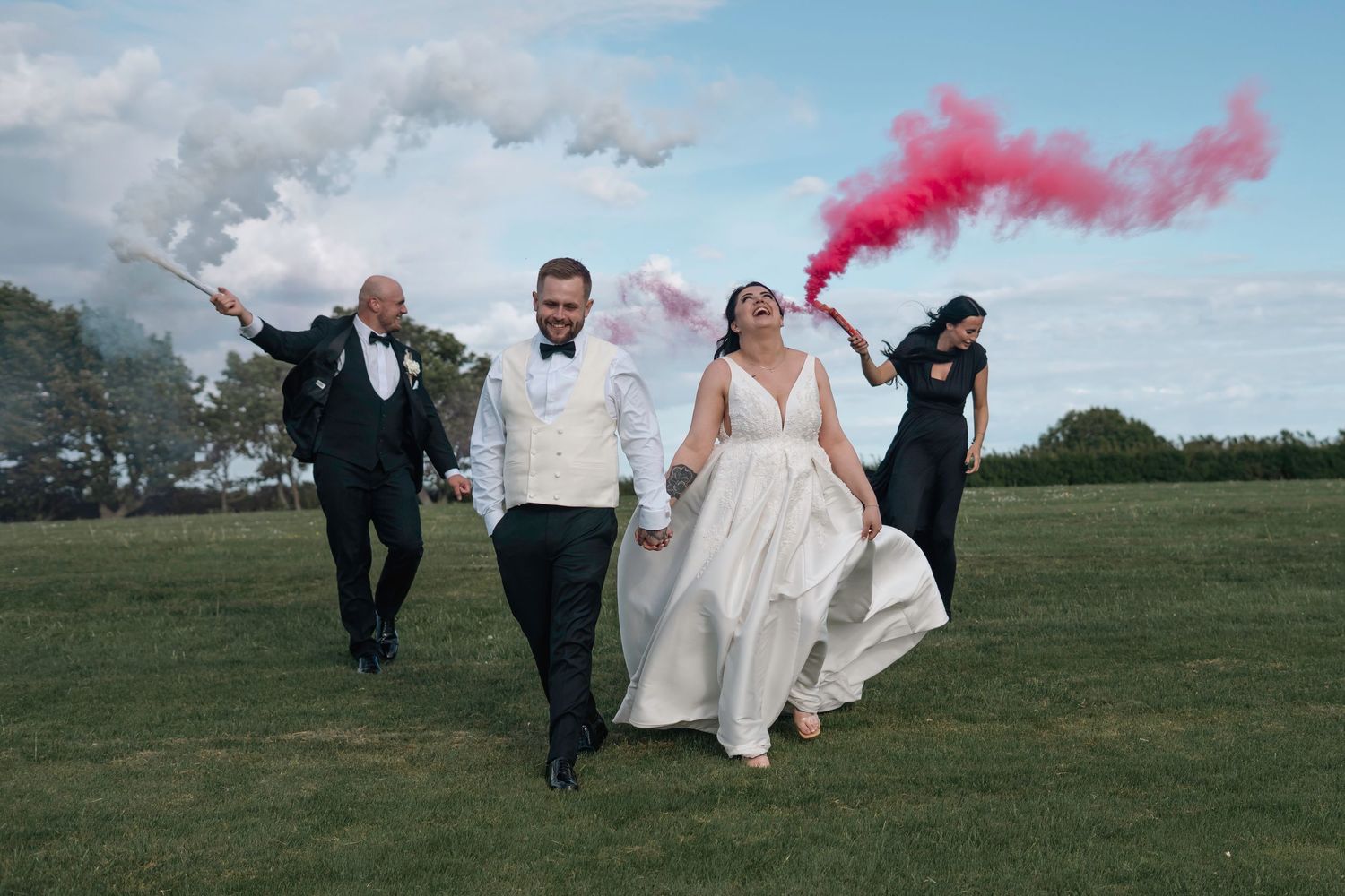 Bride and groom celebrating with red and white smoke bombs at Grand Villa Heights.