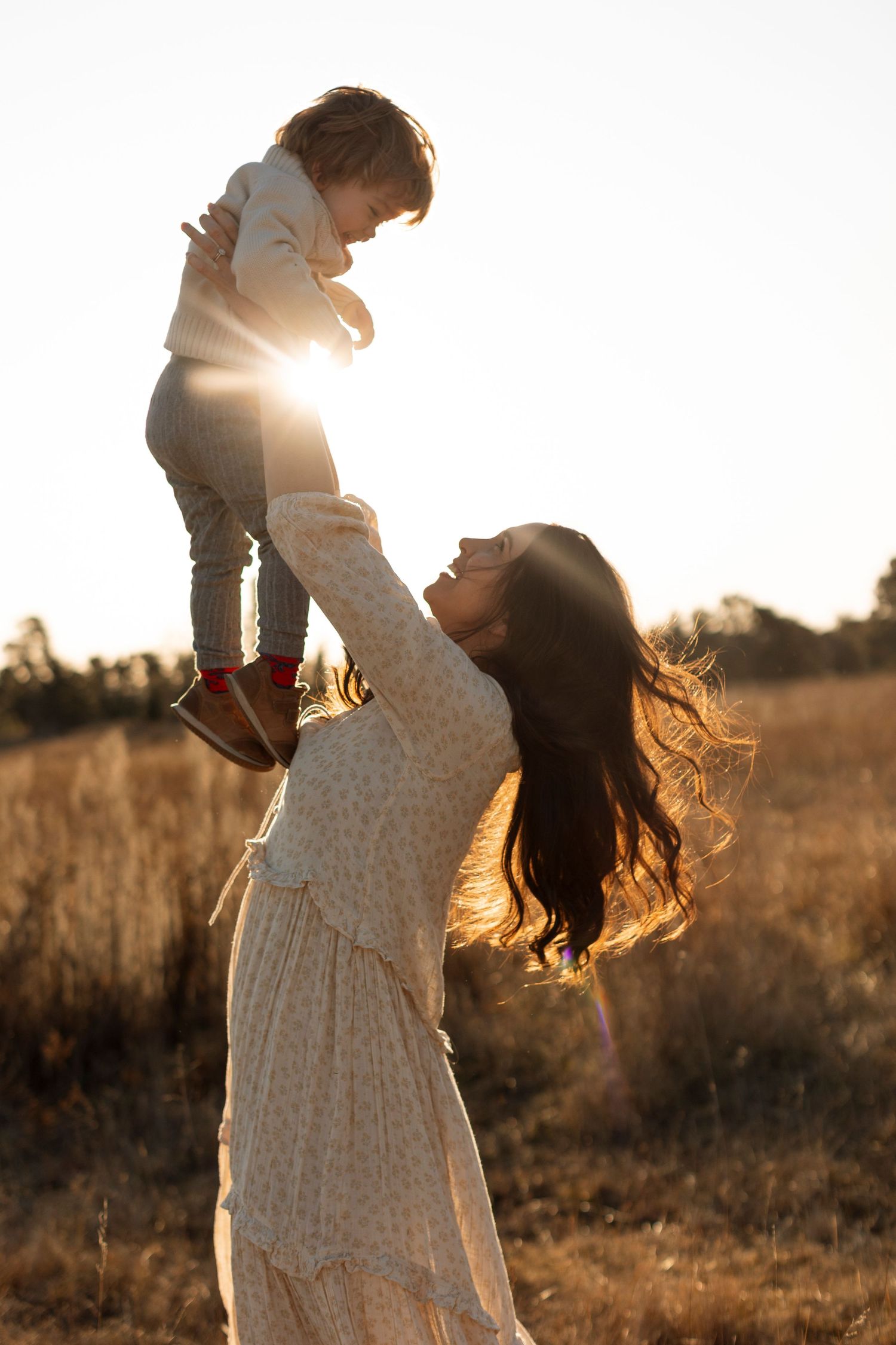 Joyful sunset moment between parent and child in flowing dress.
