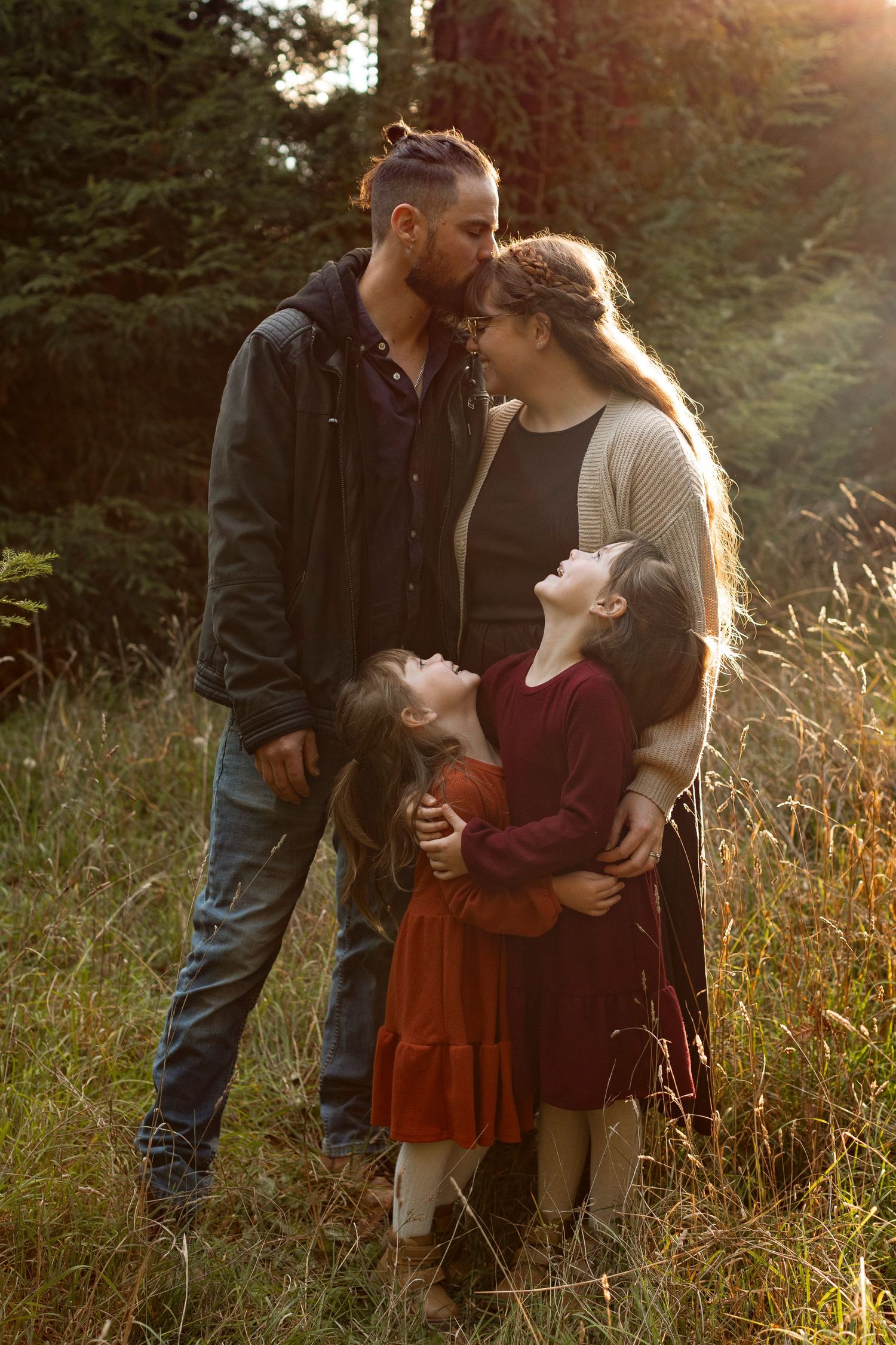 Family sharing intimate moment together in sunlit meadow at sunset.