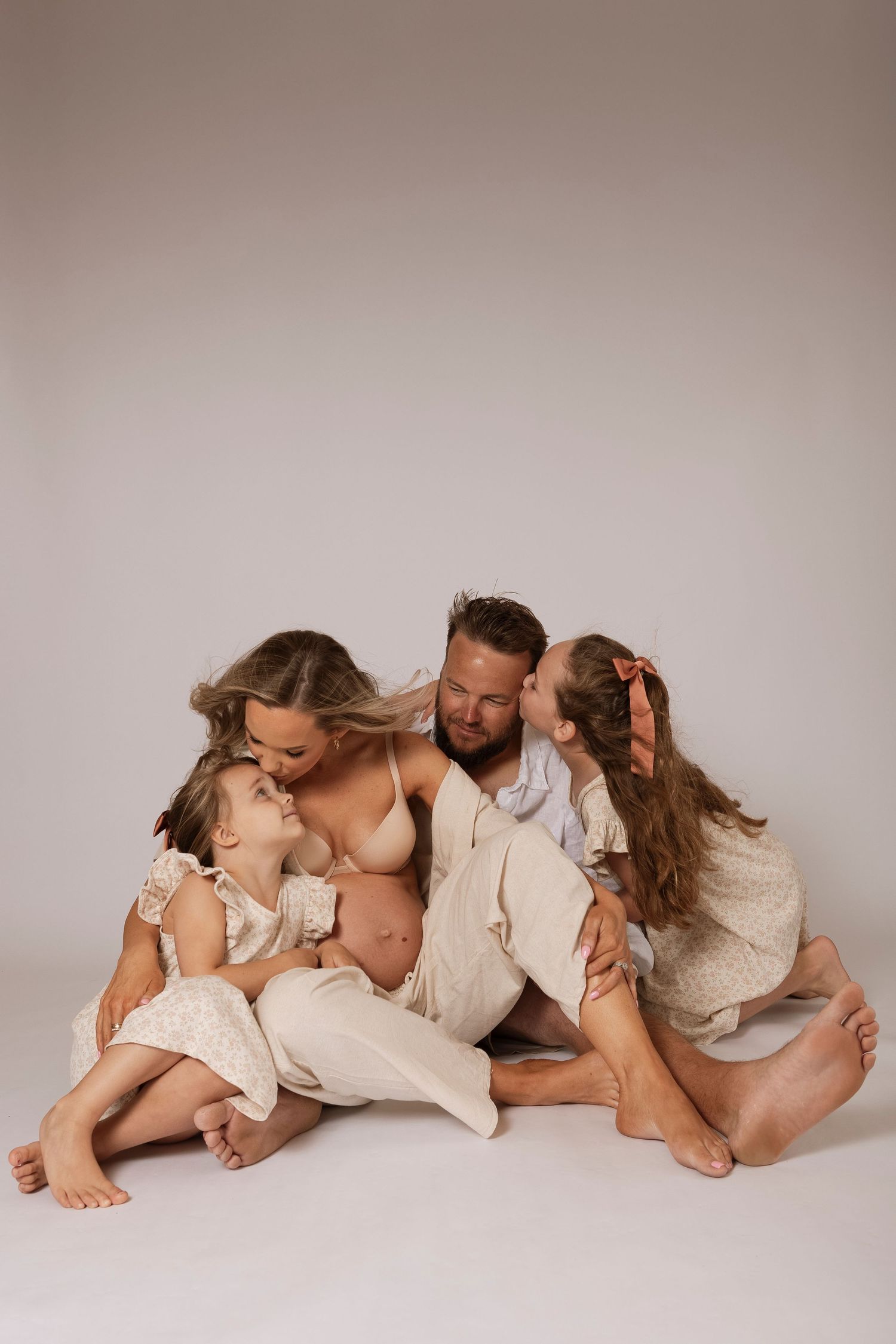 Family portrait series in neutral tones showing loving embraces on light background.