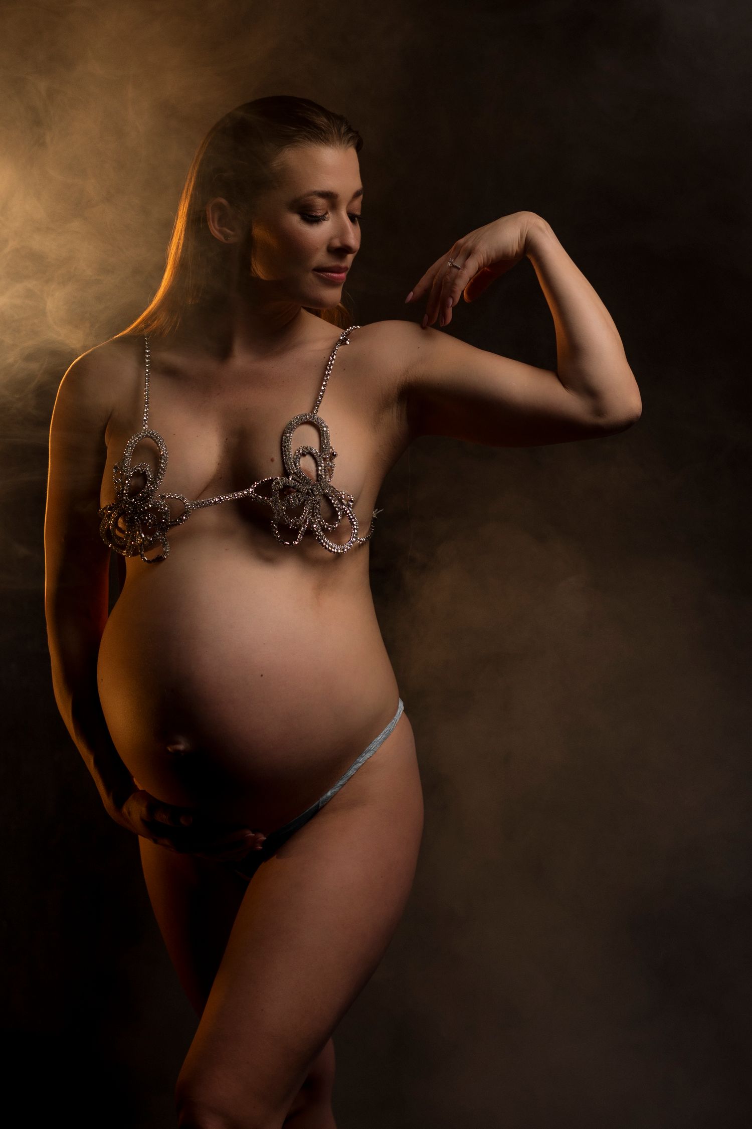 Artistic maternity photoshoot series showing silhouette of pregnant woman in warm toned lighting.