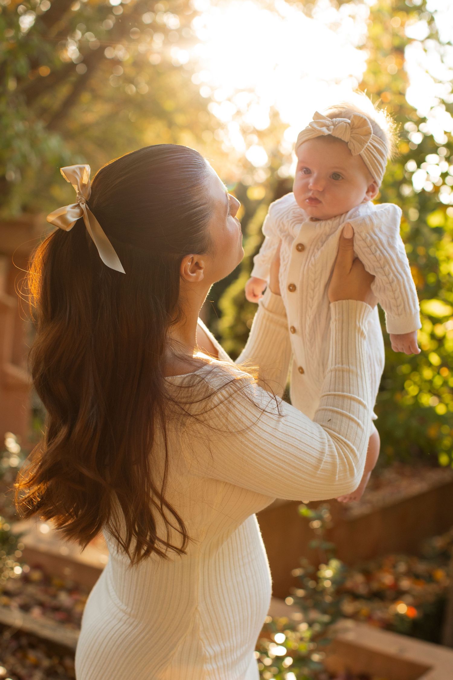 Parent and child playing together in warm sunset light wearing white sweaters.