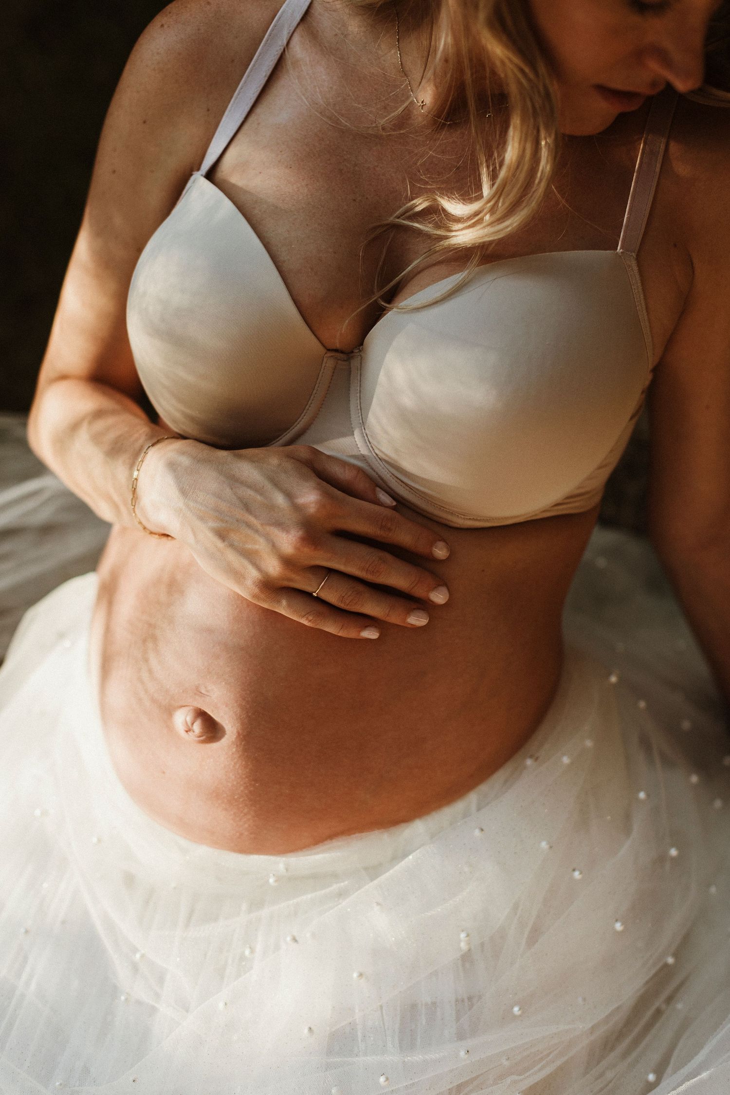 Intimate maternity portrait featuring white tulle dress detail.