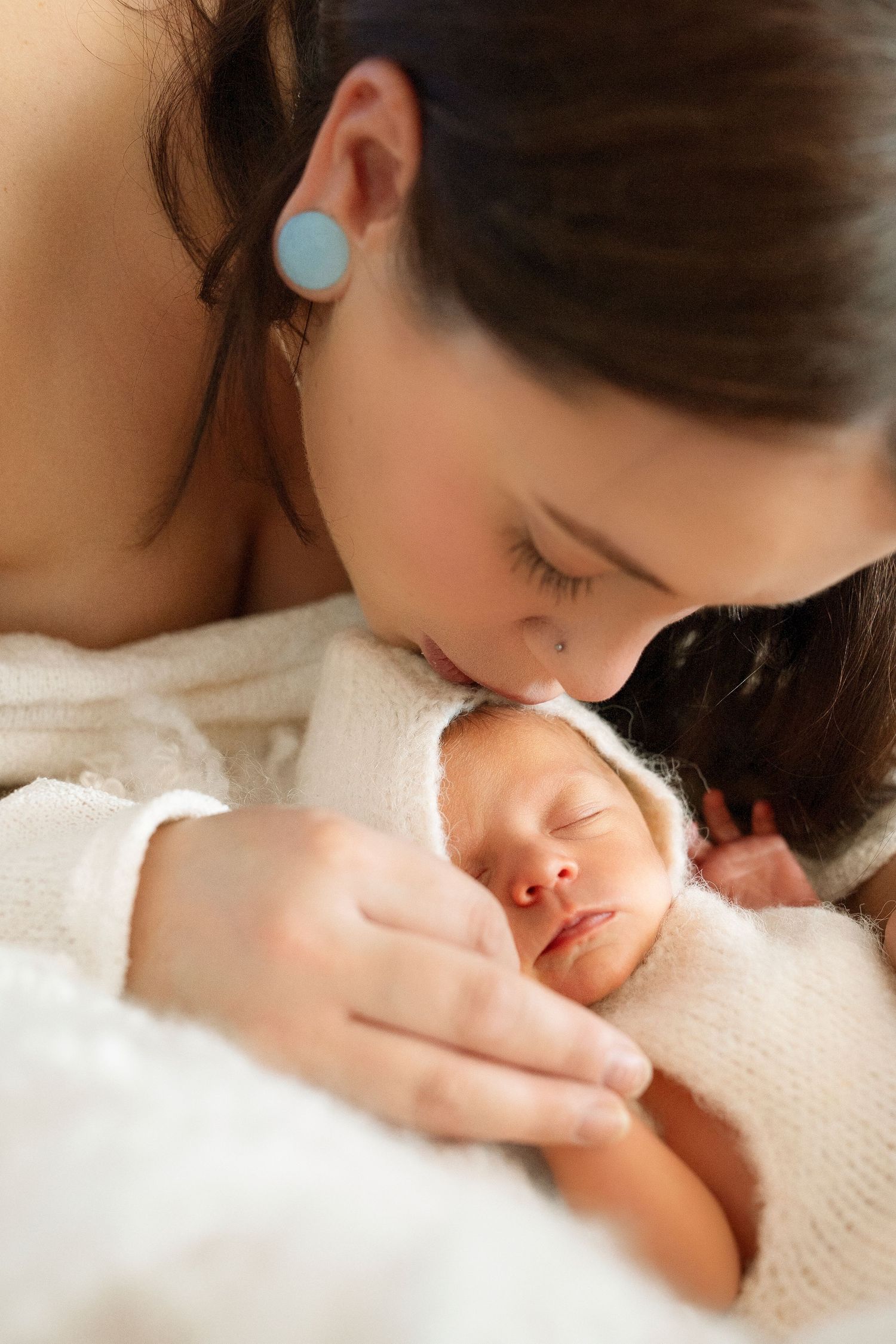 A tender moment between parent and sleeping baby in soft natural light.