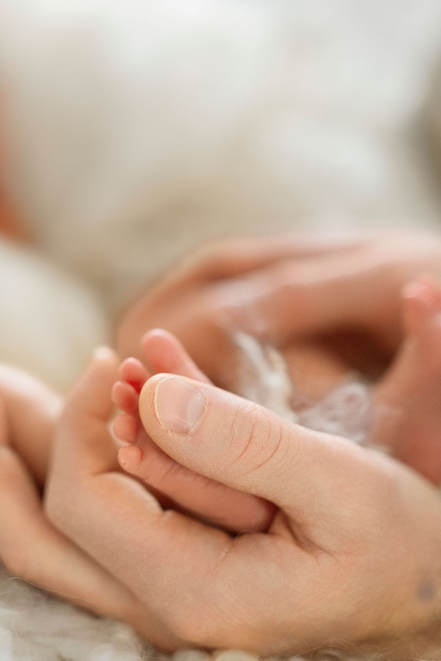 Two hands gently touching and holding each other in a caring gesture against a soft blurred background.