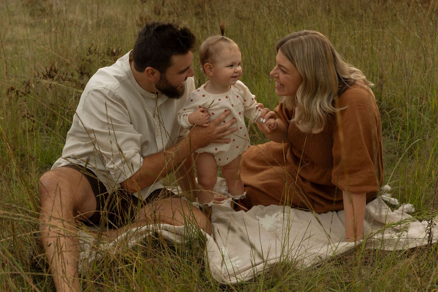 Romantic couple enjoying an intimate moment on a picnic blanket in a grassy field.