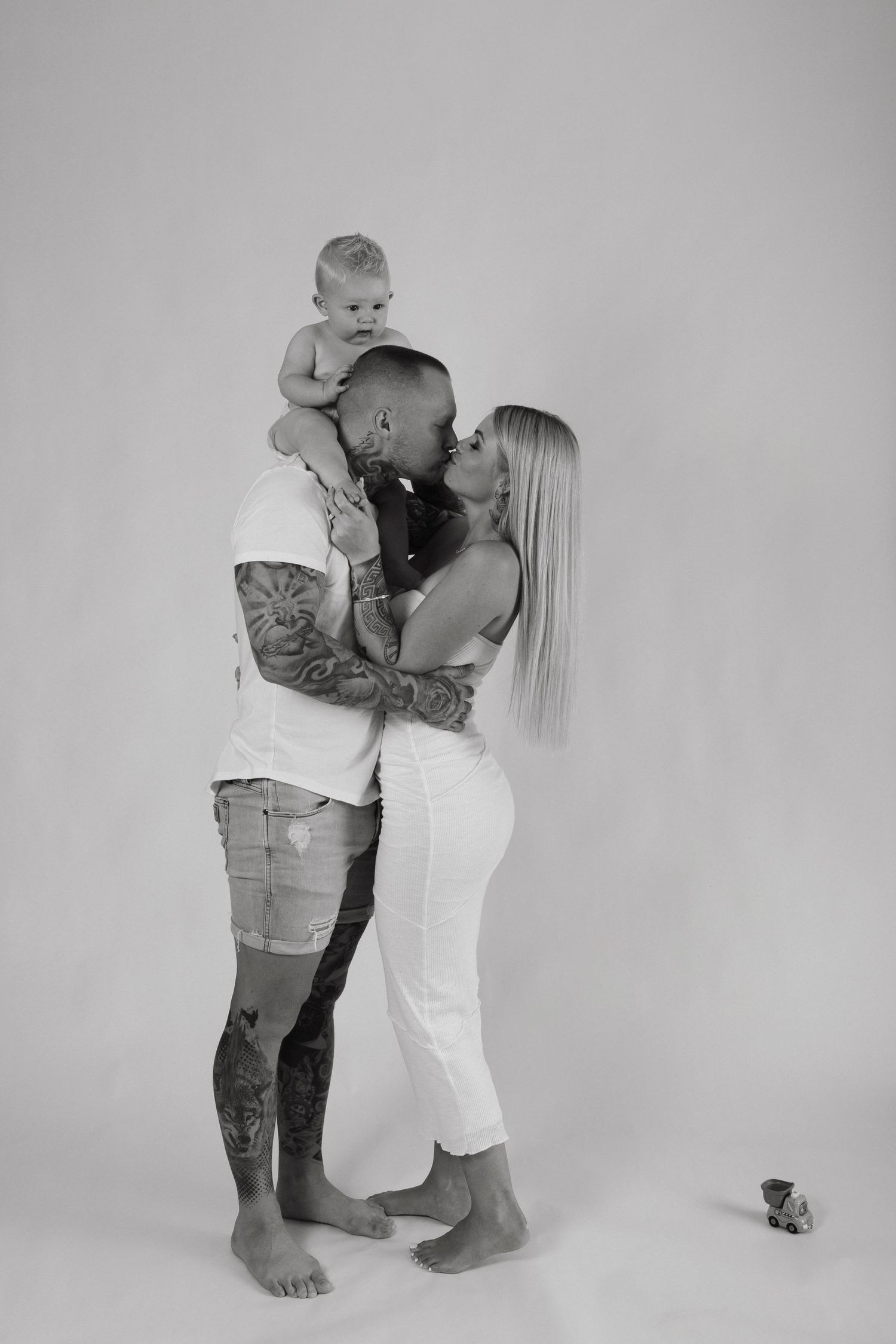 Studio family portrait series showing playful interaction between parent and child against white backdrop.