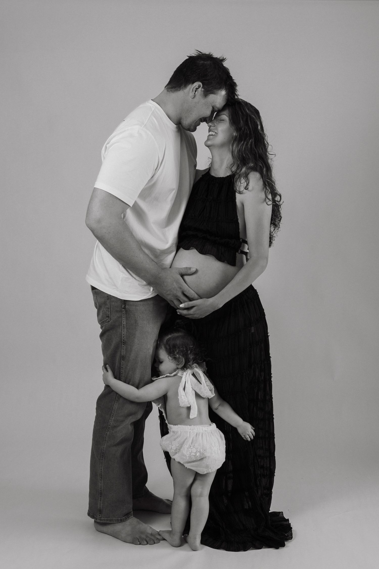 Black and white family portrait showing intimate moment during pregnancy.