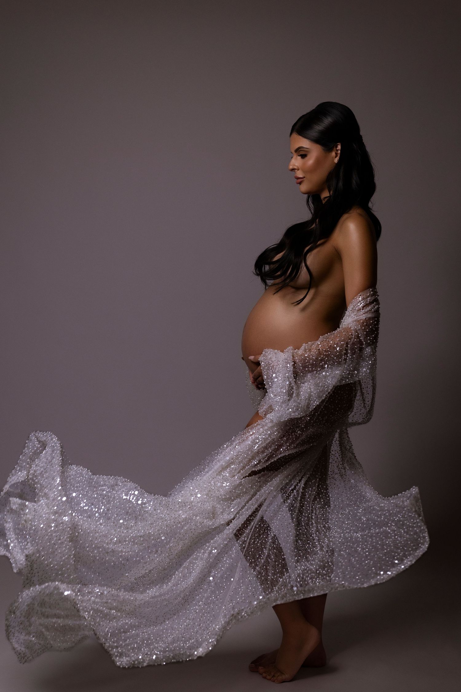 A sparkly white sequined dress flows dramatically in a series of artistic fashion photography poses against a dark background.