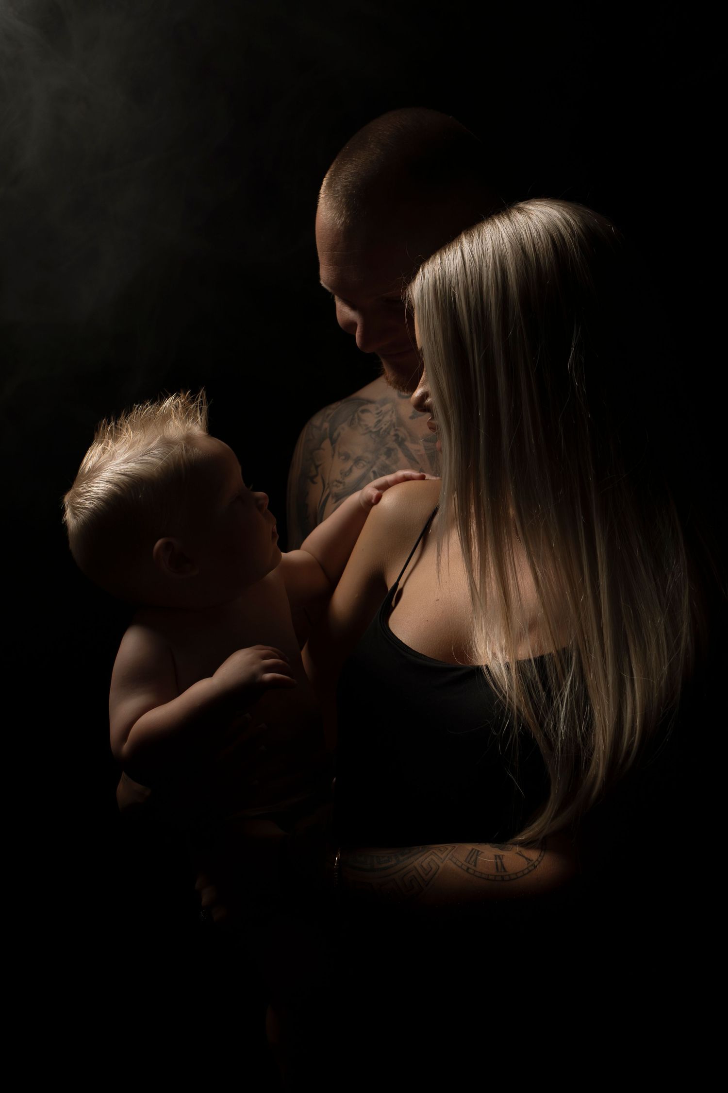 Intimate black and white portrait series showing gentle connection in low-key lighting.