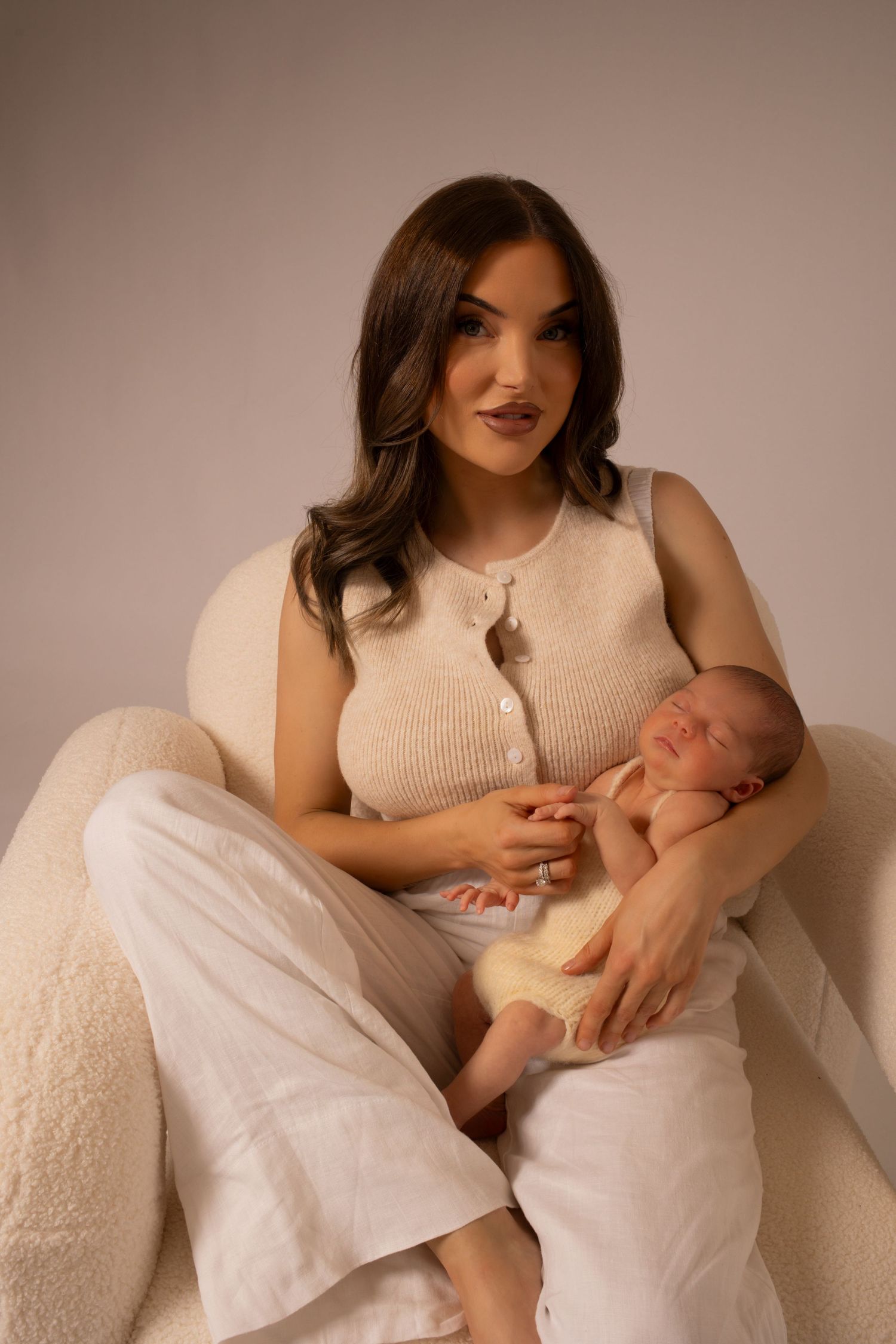 A tender moment between parent and newborn baby in soft beige tones, showcasing gentle nurturing and bonding.