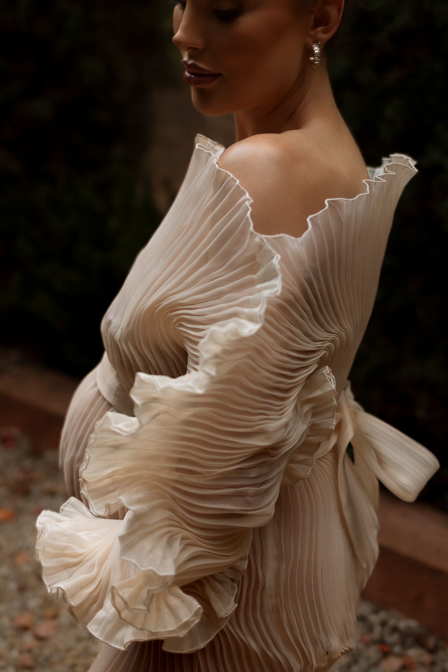 Elegant pleated white dress with ruffled details photographed in artistic close-up.