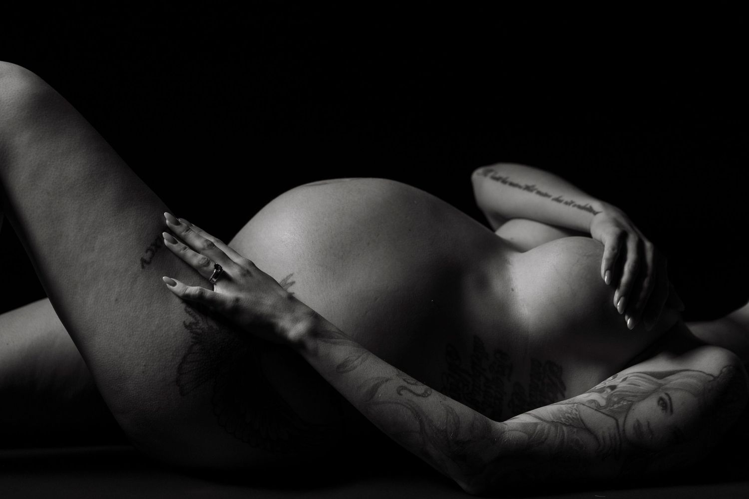 Black and white artistic photo of pregnant belly in dramatic lighting.