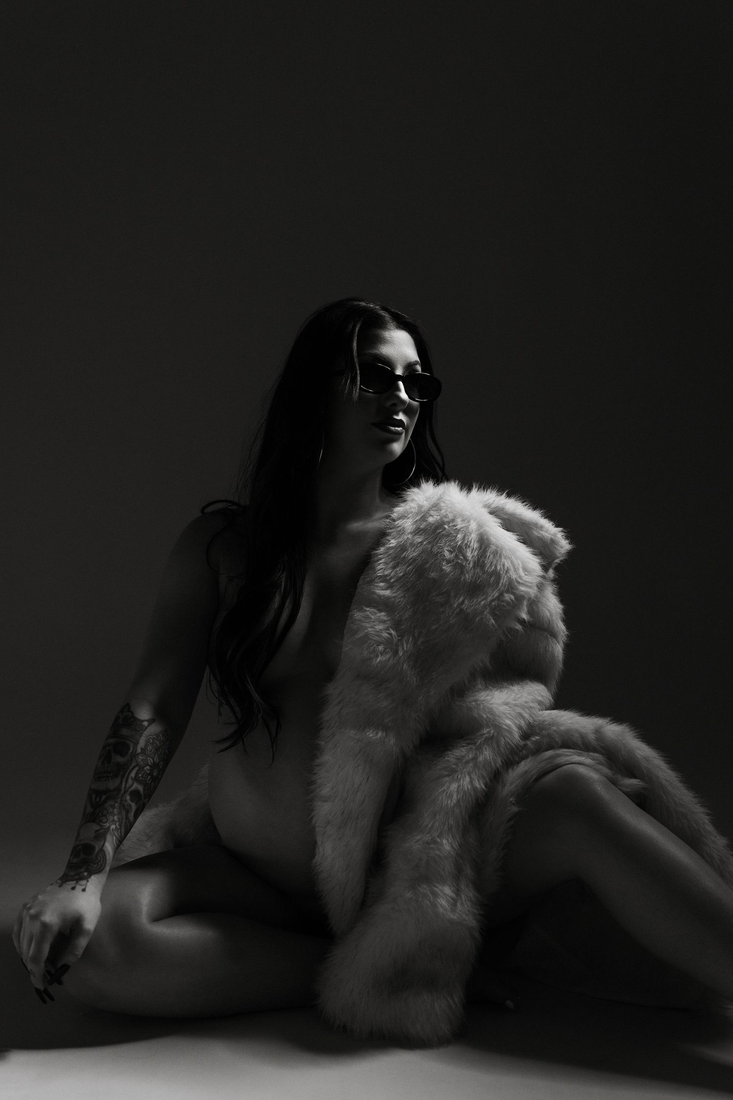 A black and white artistic photo series showing a figure in dark lighting with white fur fabric creating dramatic contrast.