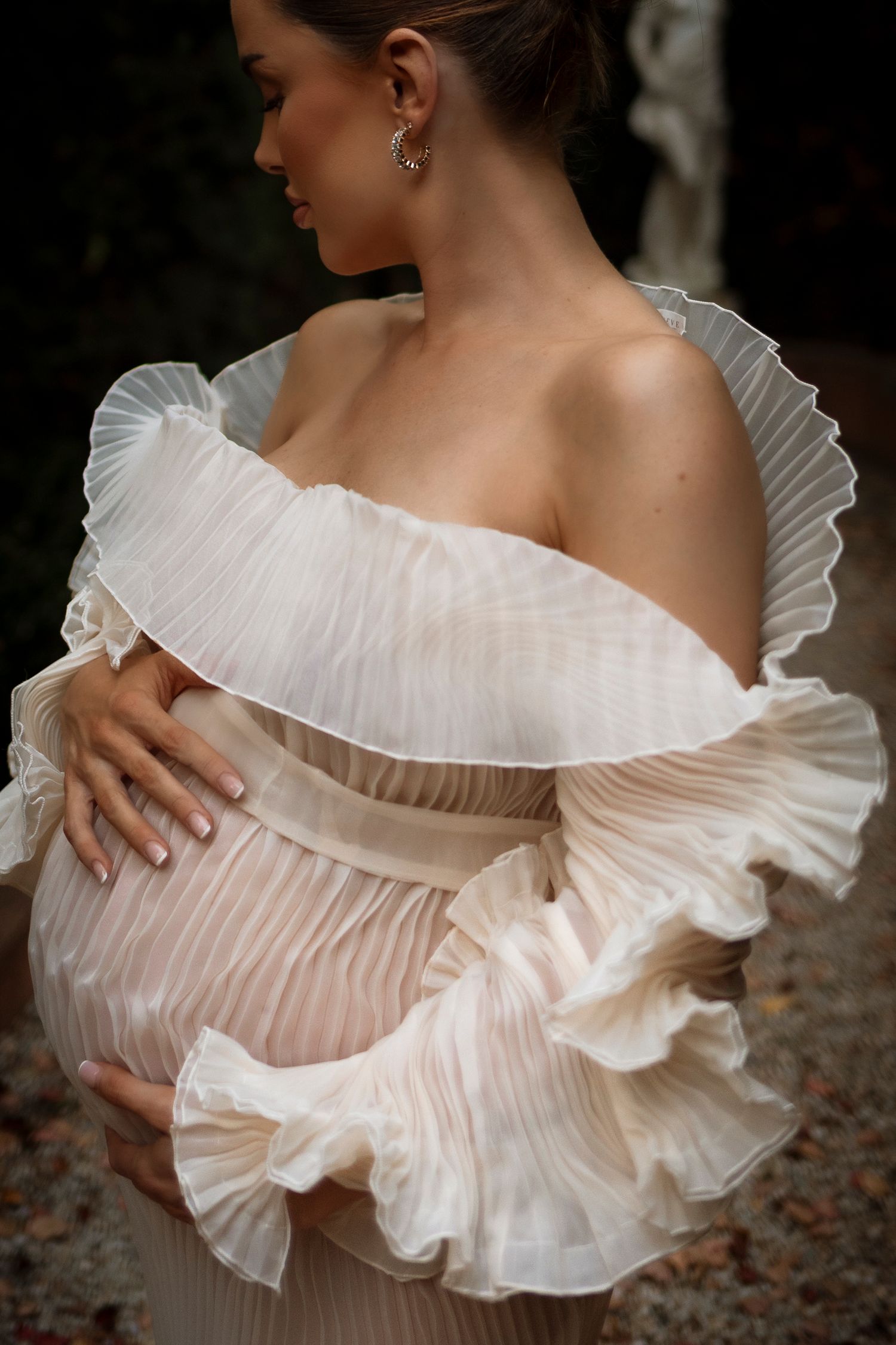 Woman in ruffled white dress showcases elegant pleated neckline detail in artistic close-up shots.