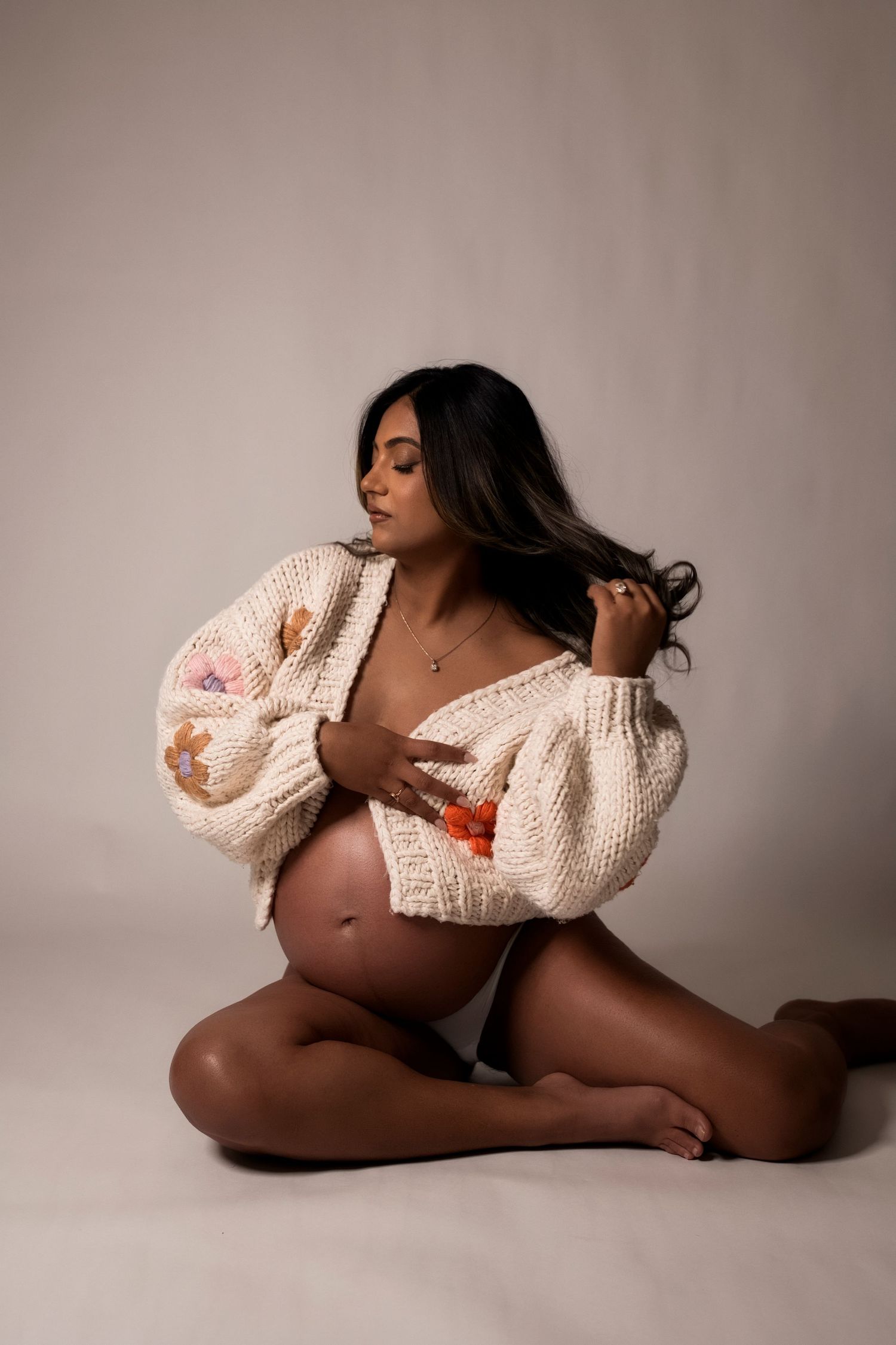 Artistic boudoir photo series showing figure in cream knit sweater against neutral backdrop in various poses.