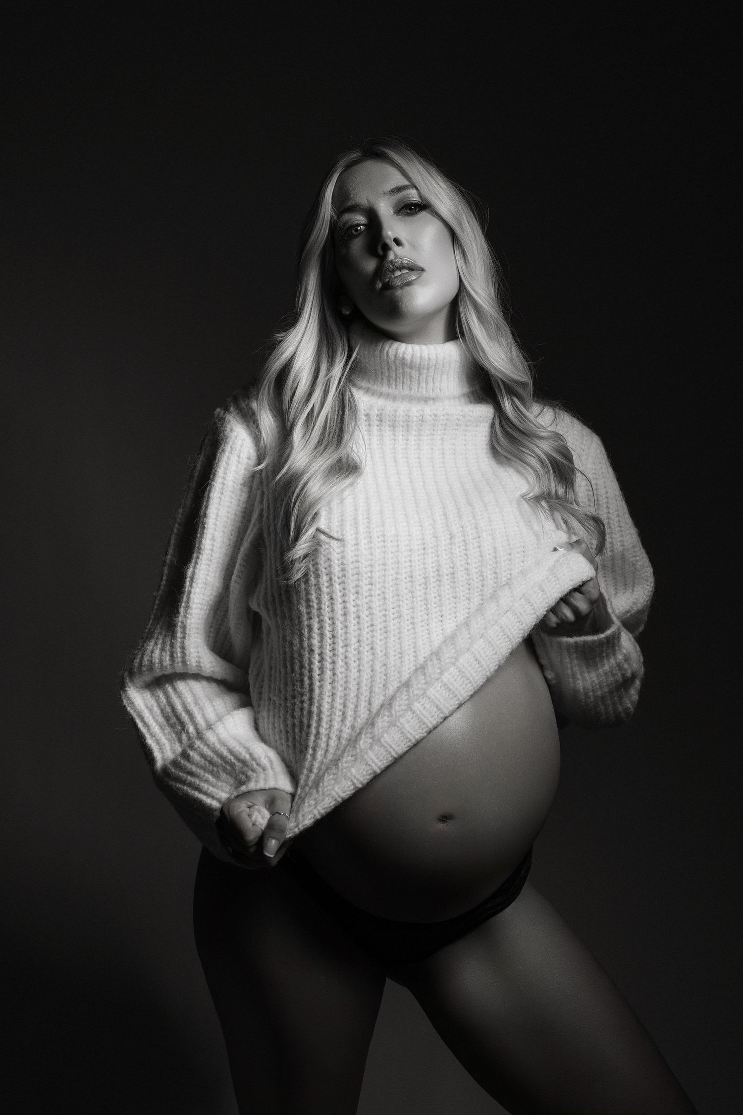 Dramatic black and white fashion photo series showing a model in a white turtleneck sweater posing against dark background.