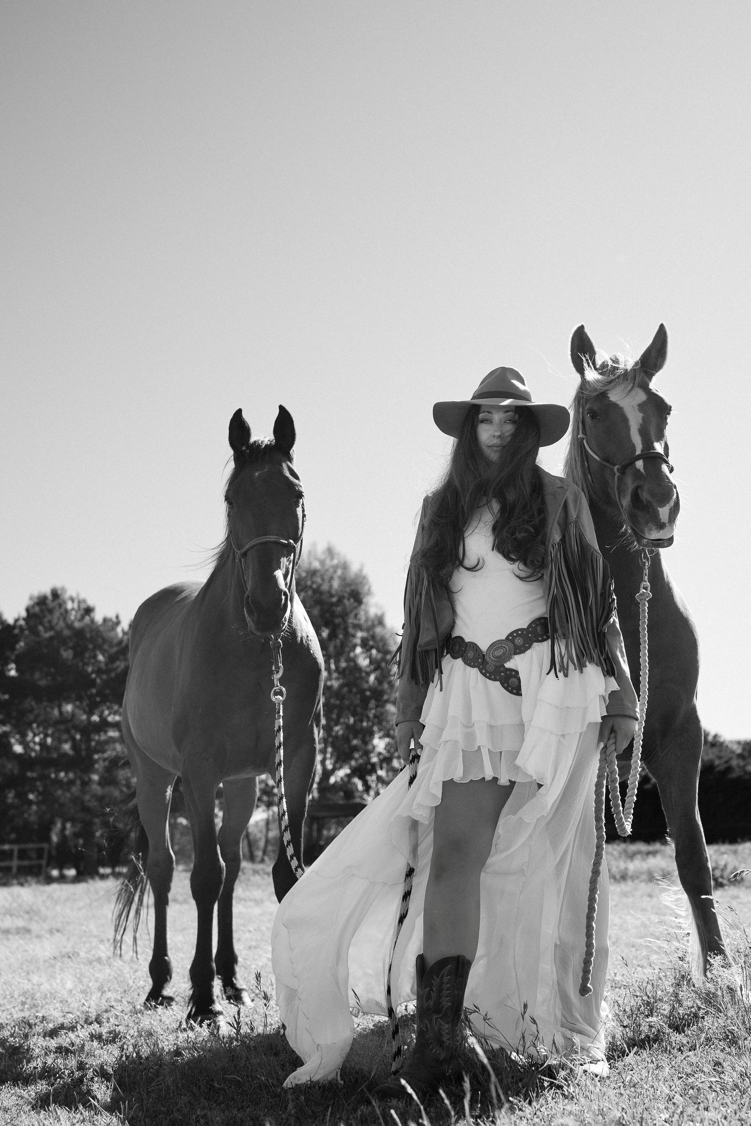 Black and white photos of people in white dresses posing with horses in a rustic outdoor setting.