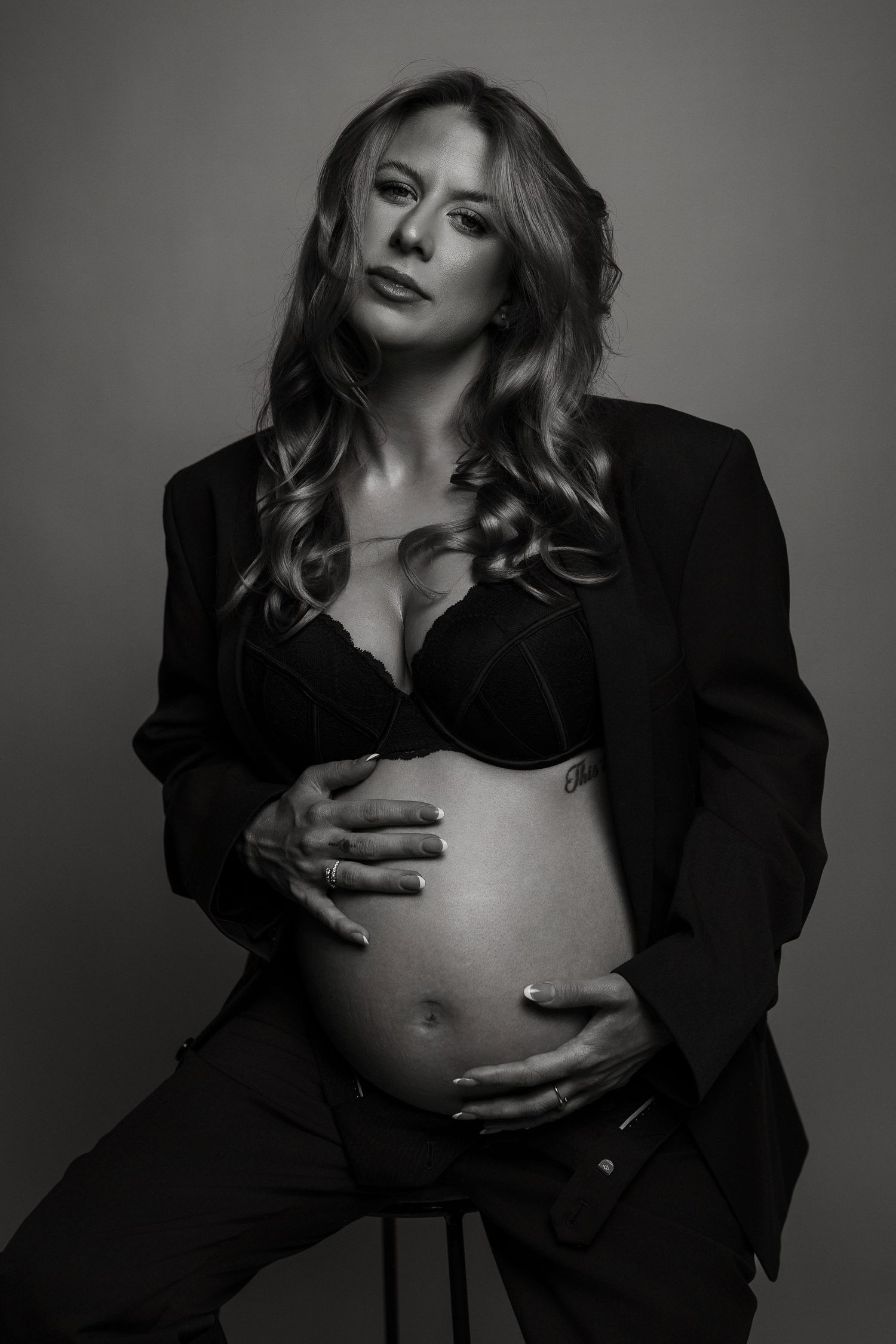 Black and white maternity portraits with dramatic lighting and business attire styling.