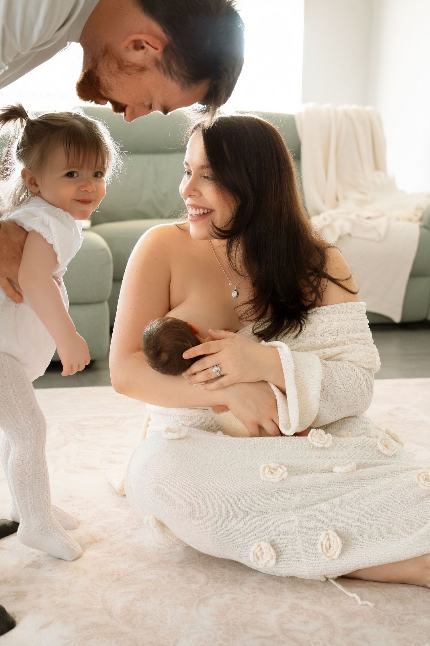A family shares an intimate moment together on a white carpet while relaxing at home.
