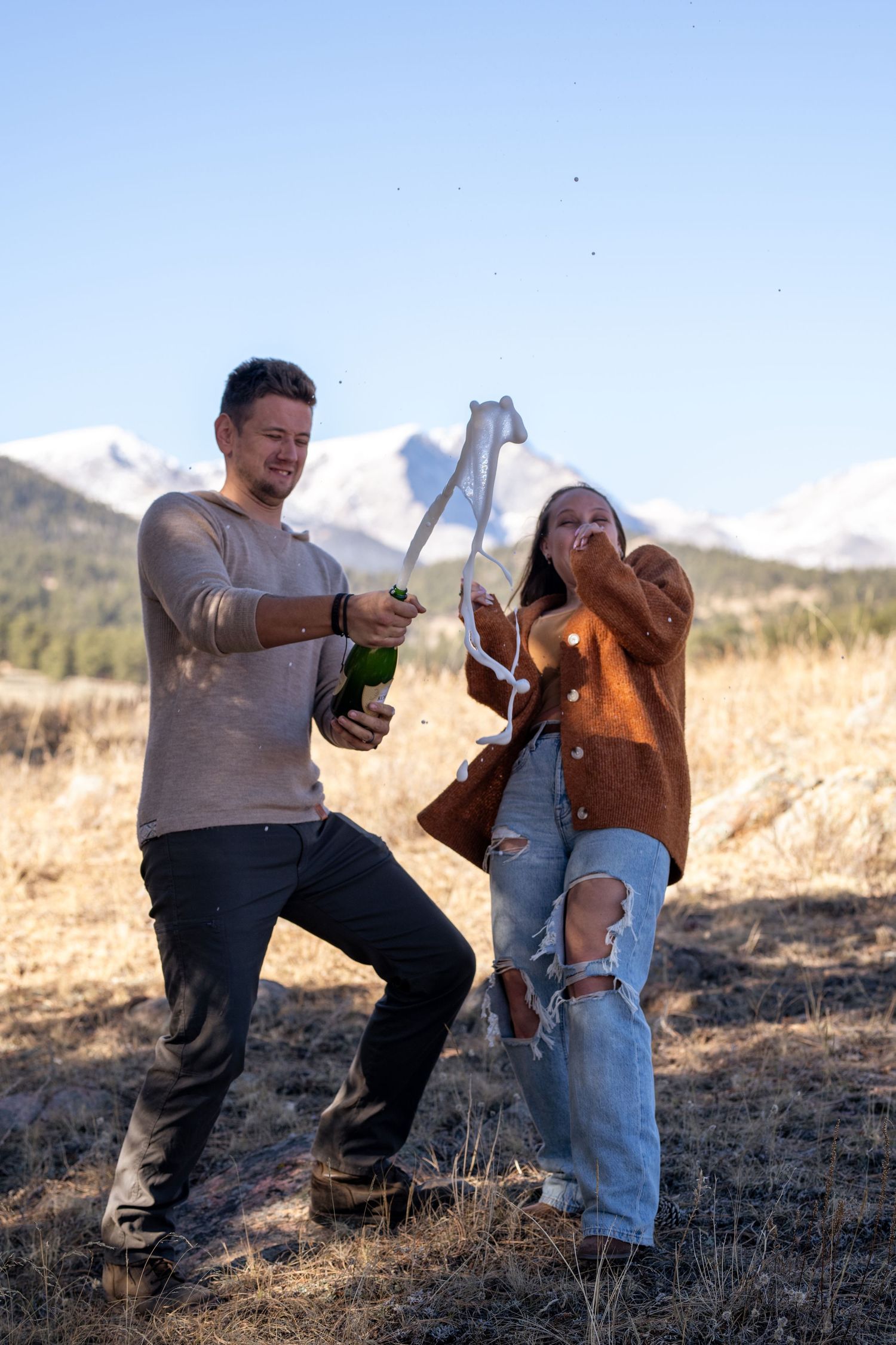 Celebratory moment with champagne in an open field with mountain views and natural scenery.