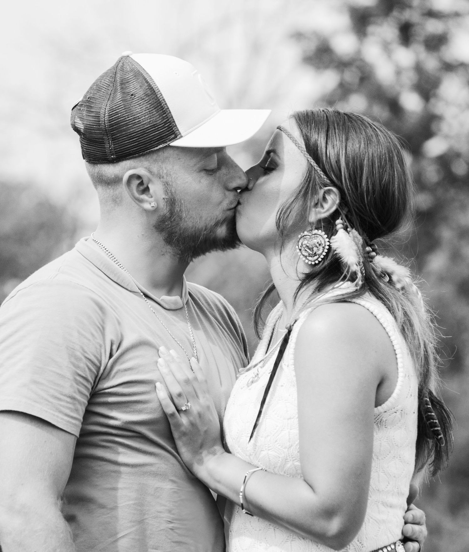 Romantic black and white photo of couple sharing an intimate kiss outdoors.