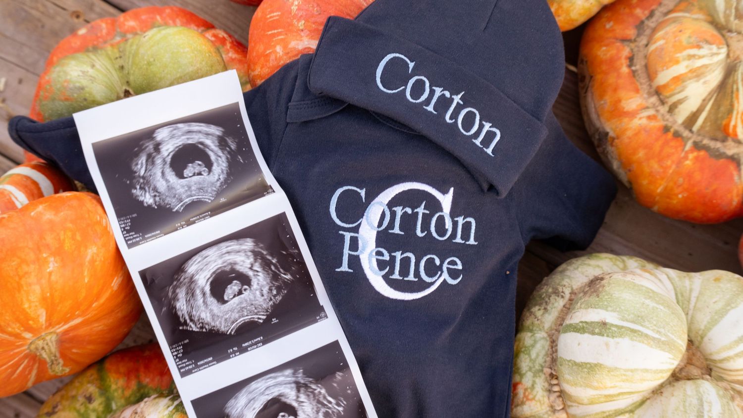 Pregnancy announcement with ultrasound photos and personalized baby items surrounded by orange pumpkins.