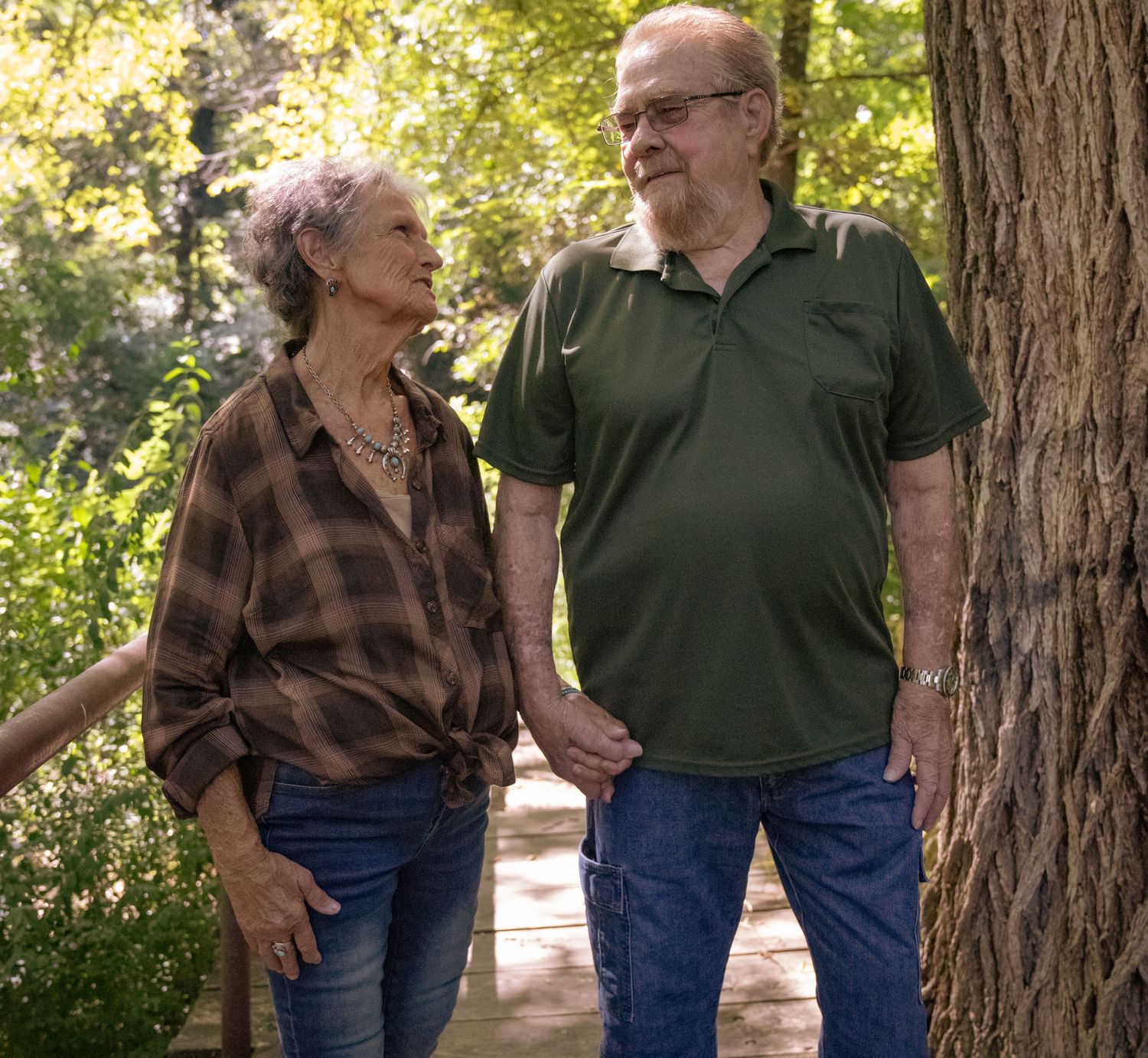 A mature couple sharing a joyful moment while walking along a wooded trail.