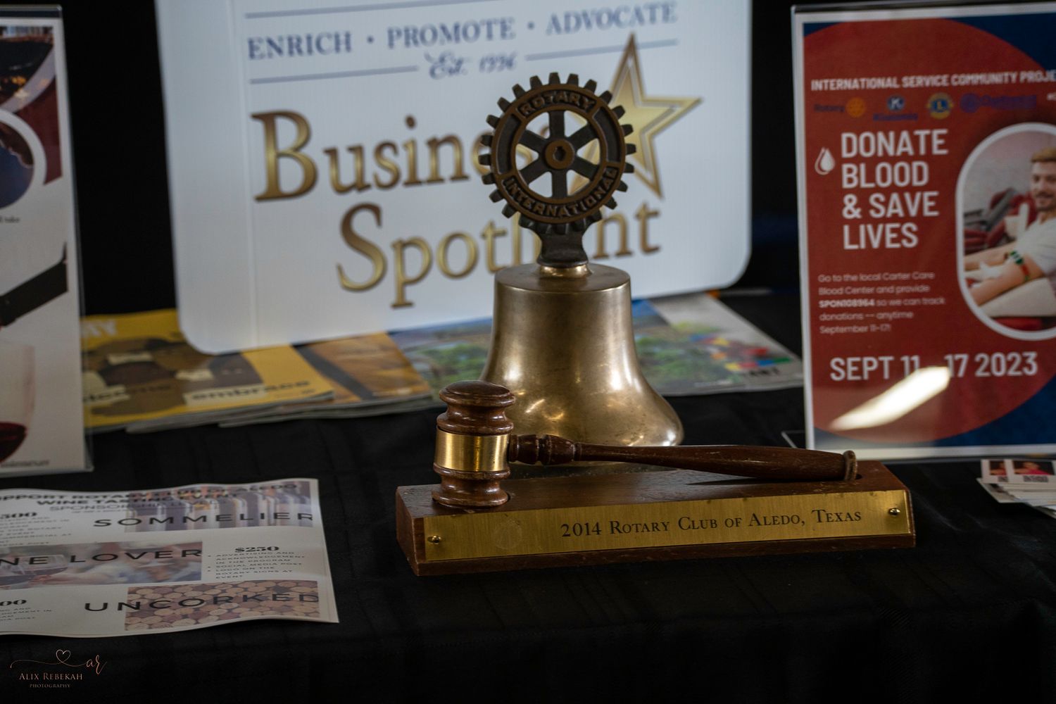 Gold Rotary Club bell trophy displayed on dark surface with Business Spotlight signage.