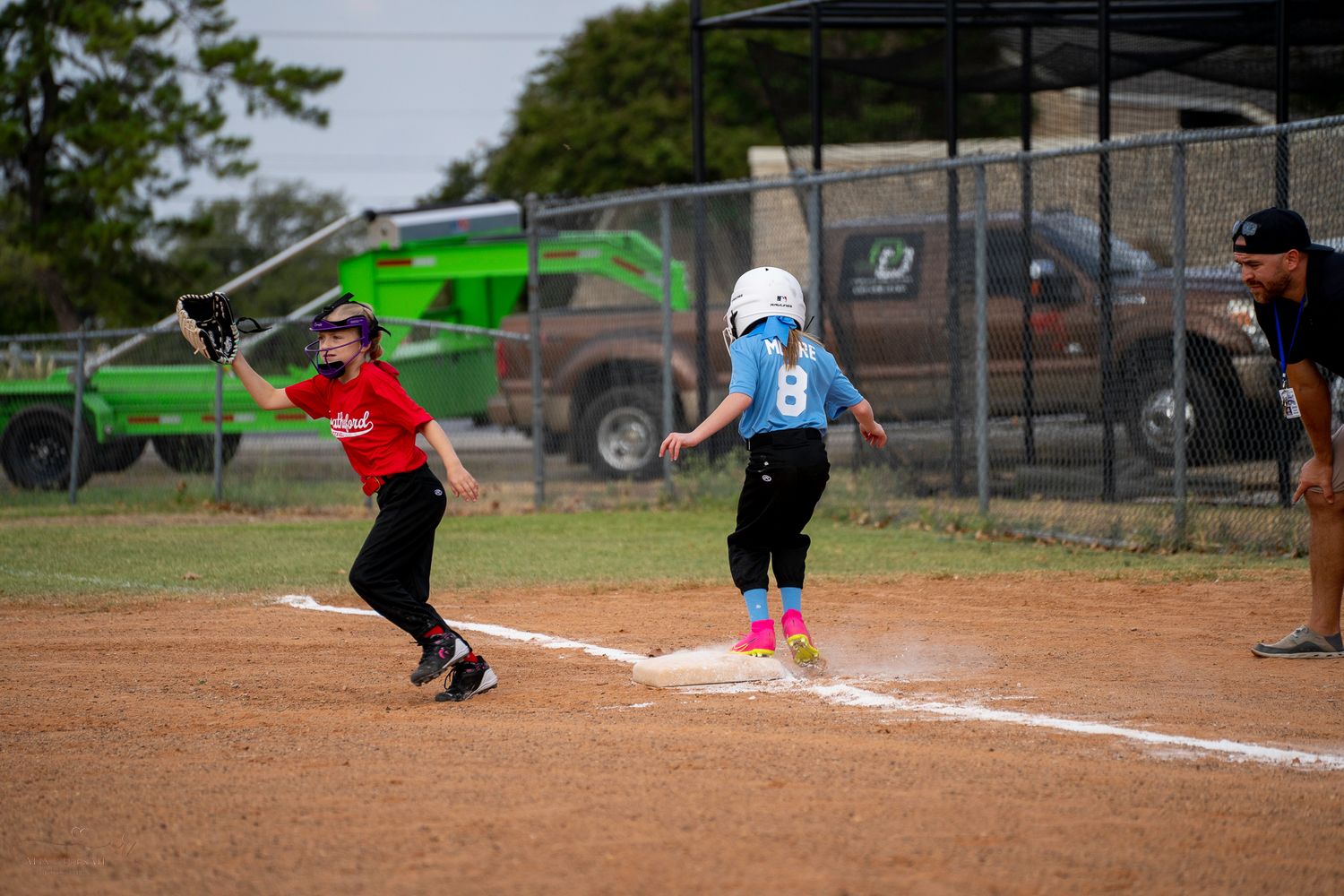 A softball player slides into home plate during a game while attempting to score a run.