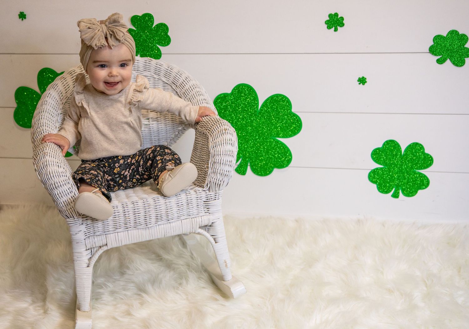 A collage shows a baby on a white rug with St. Patrick's Day green shamrock decorations on the wall.