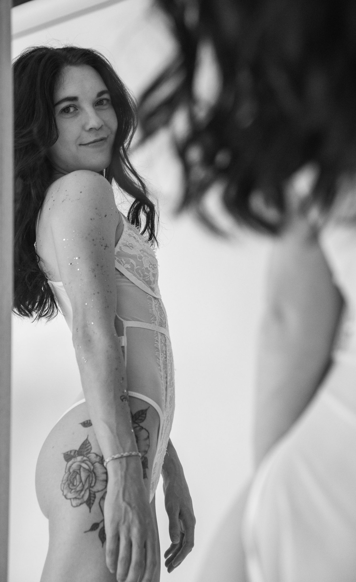 Black and white artistic portrait featuring delicate lace details and floral body art.