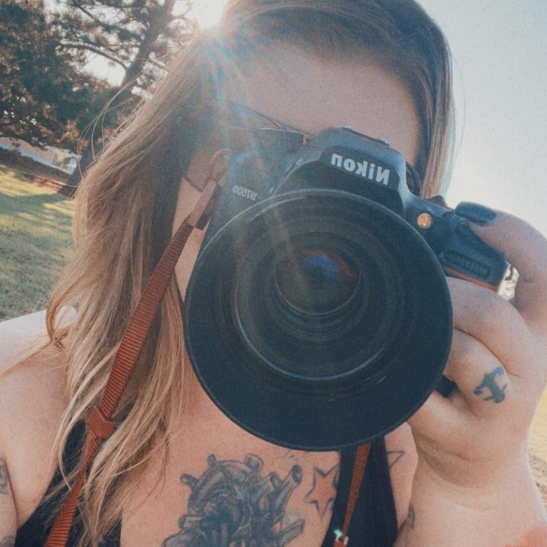 Close up view of a Nikon camera lens being held up for a selfie style photo.
